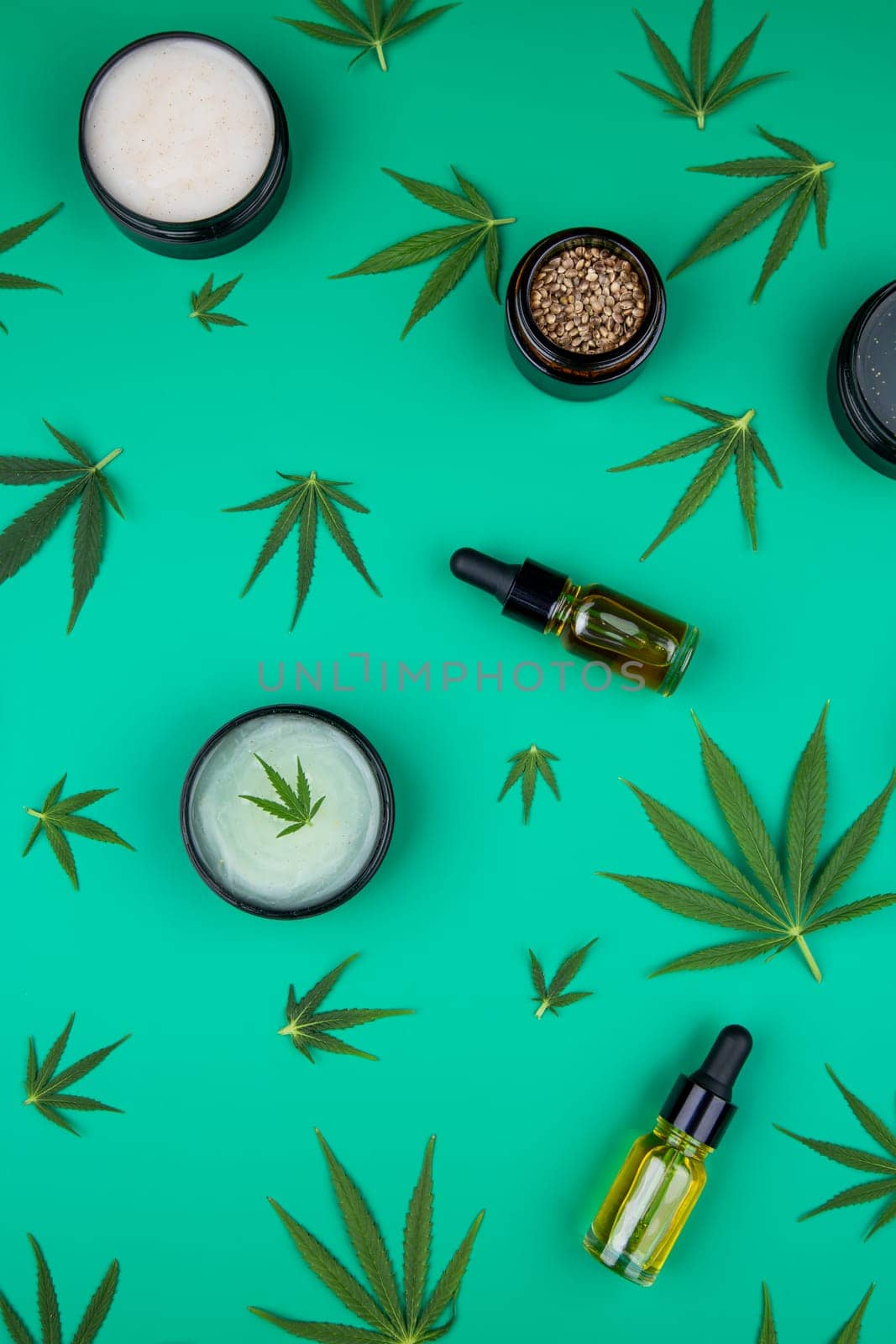 Flat lay composition with hemp oil and hemp leaves on green background