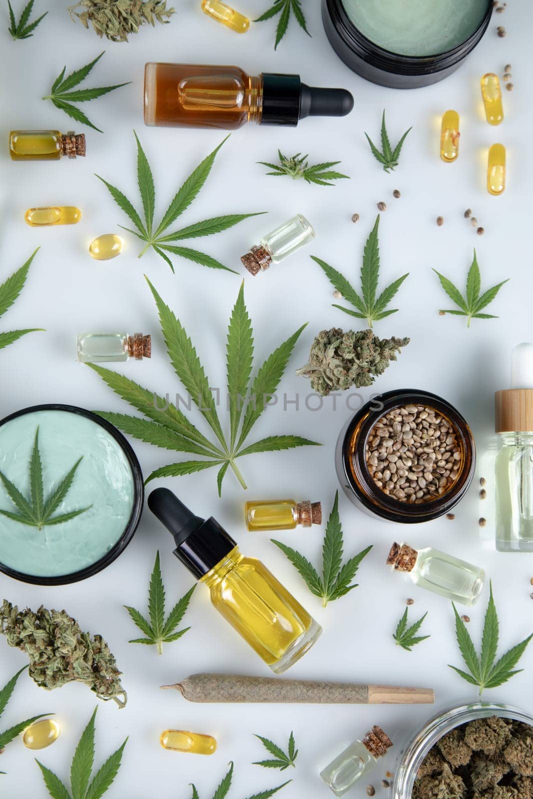 Flat lay composition with marijuana leaves, bottle of oil, cannabis on cbd, white background