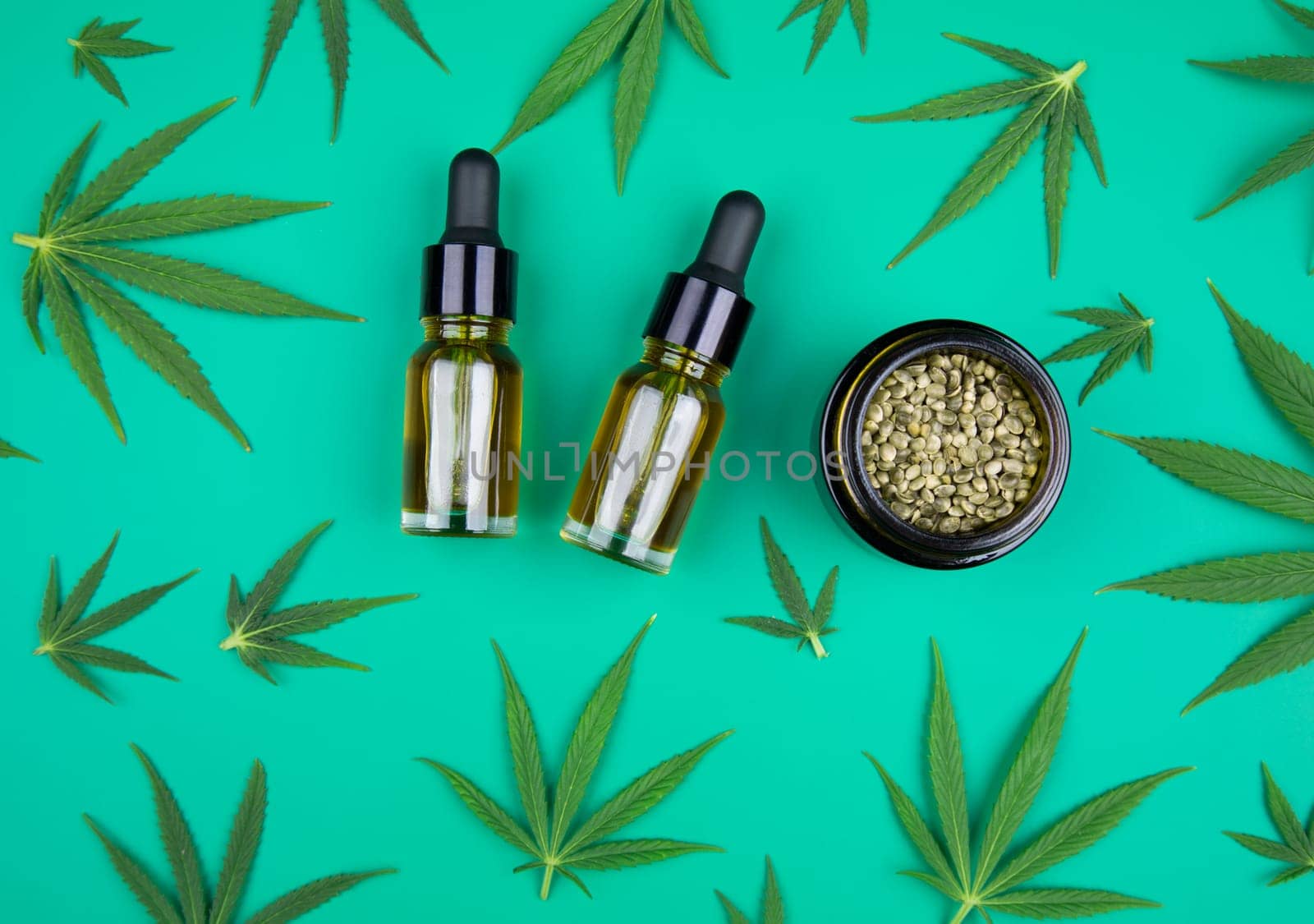 Flat lay composition of marijuana and hemp seeds on color green background