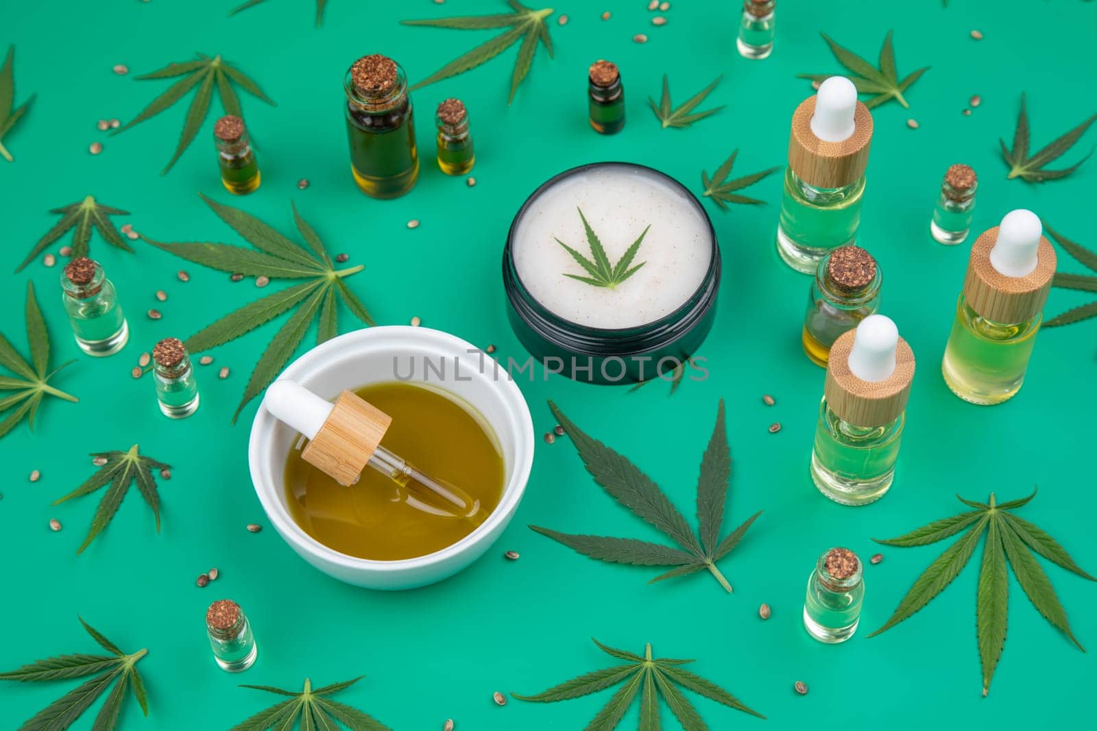 Flat lay composition of marijuana and hemp seeds on color green background