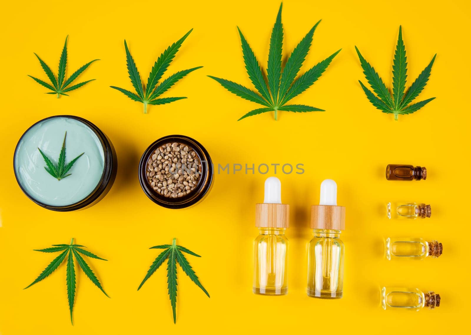 Set of essential oil in a glass bottle, with a pipette on a yellow background, top view