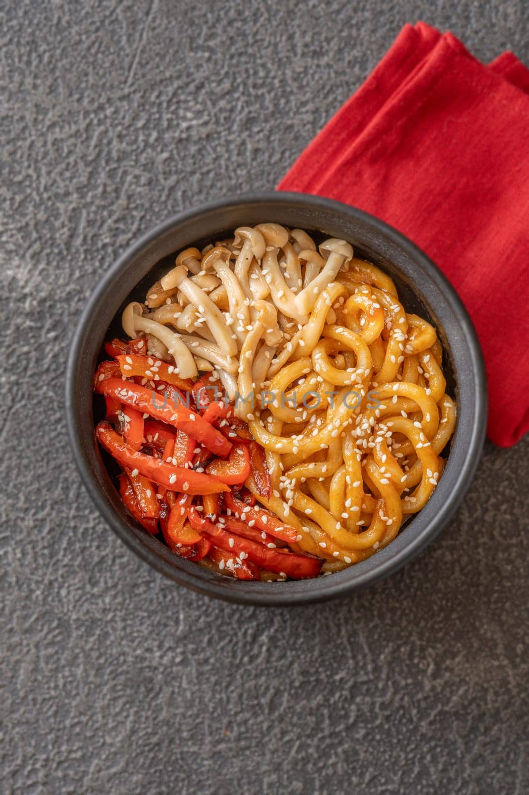 Bowl of udon noodles with bell pepper and mushrooms