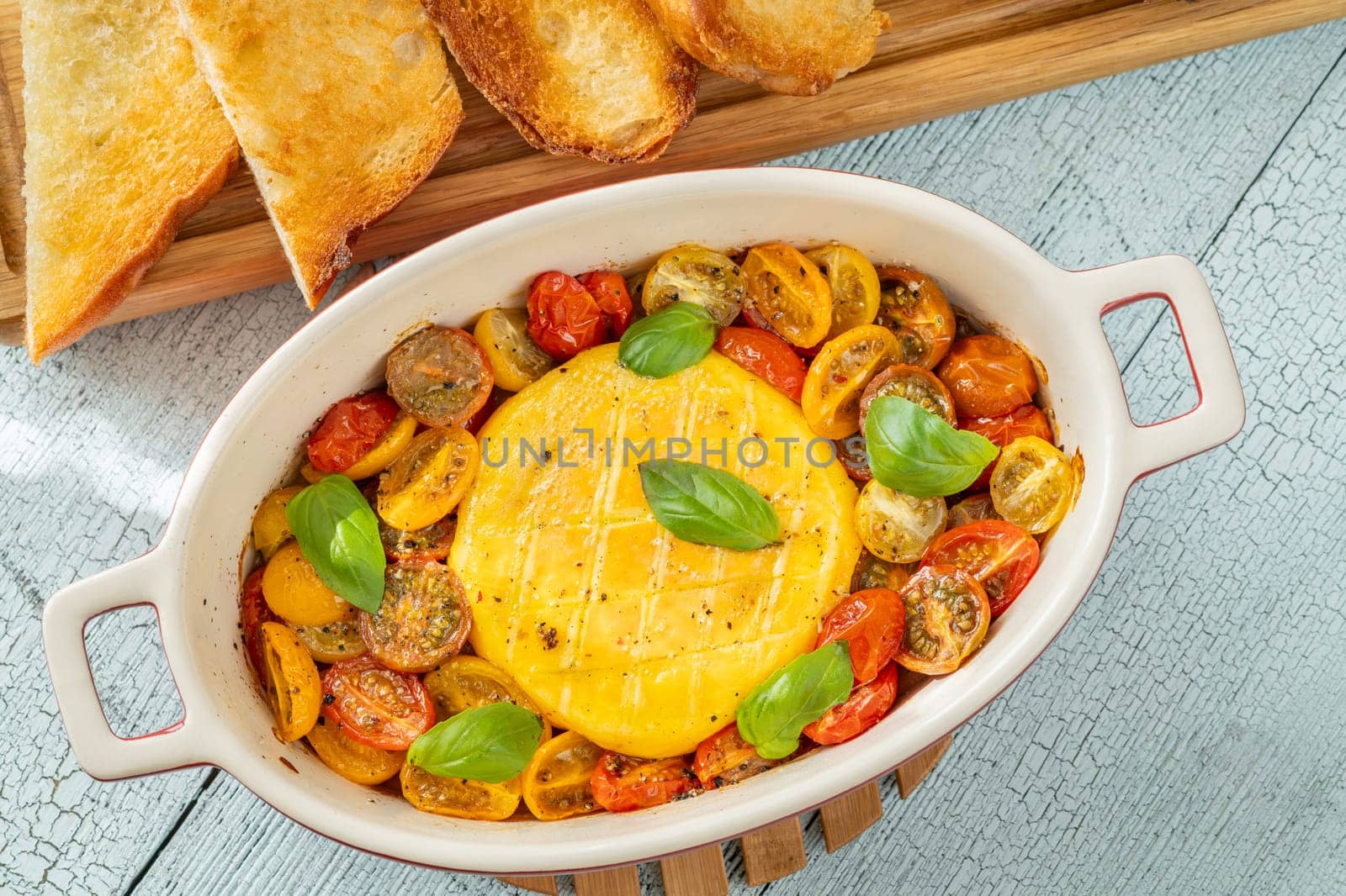Baked camembert cheese with cherry tomatoes and basil