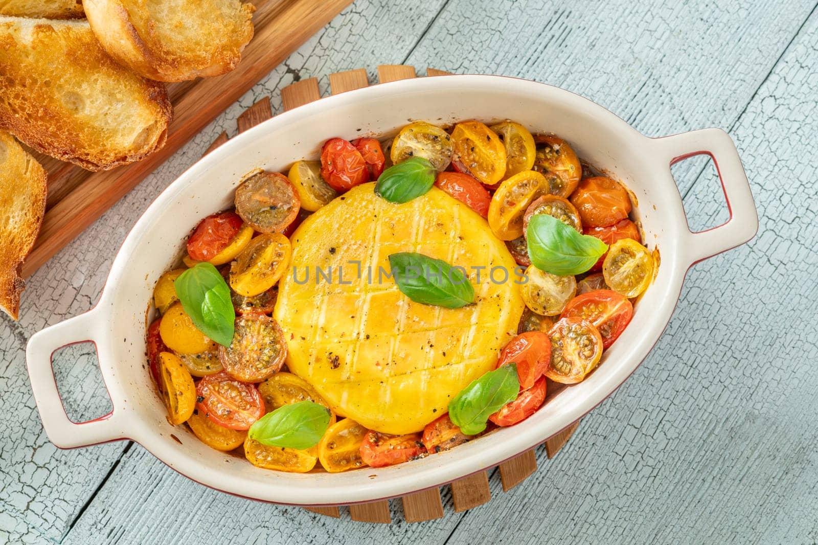 Baked camembert cheese with cherry tomatoes and basil