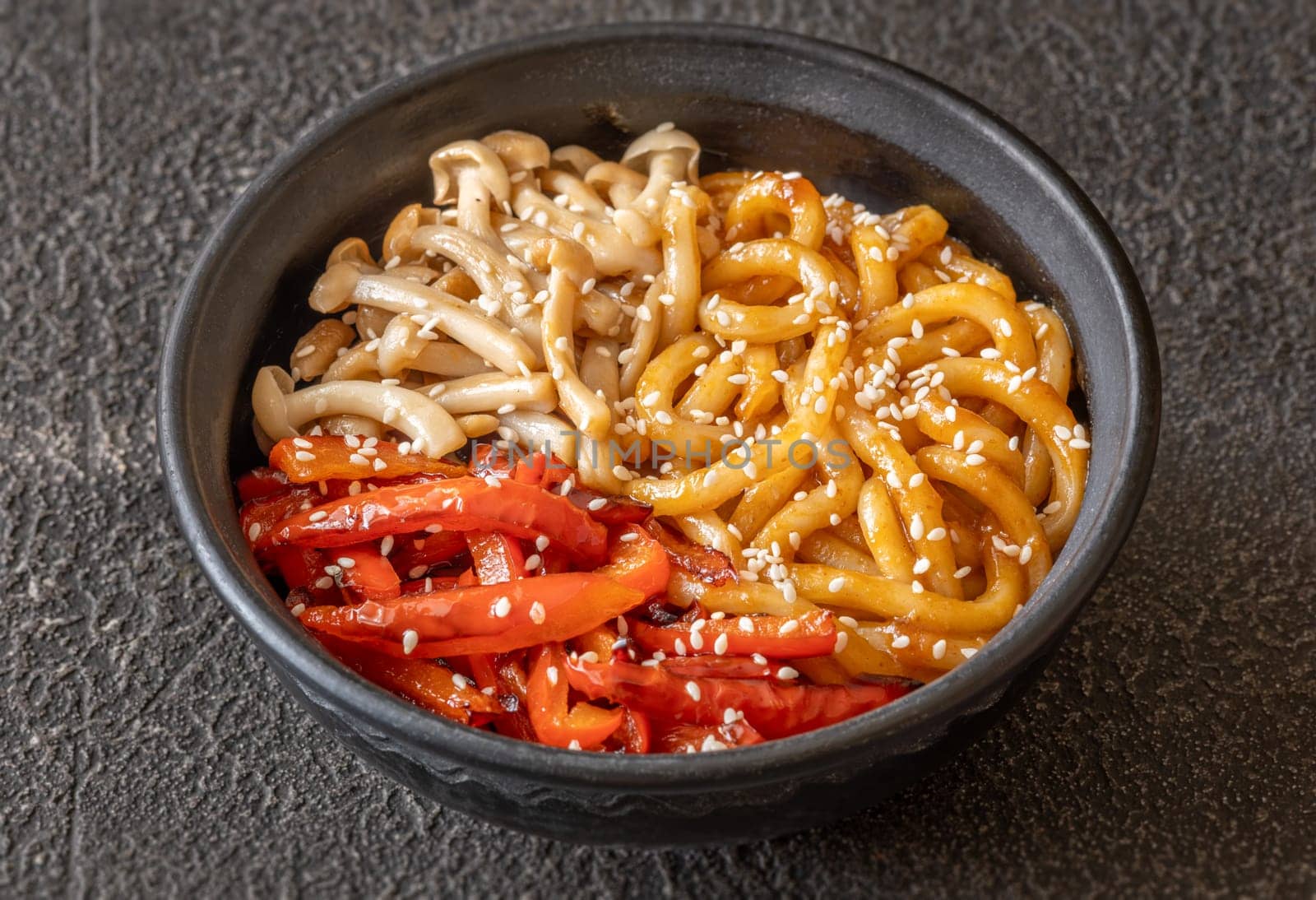Bowl of udon noodles with bell pepper and mushrooms