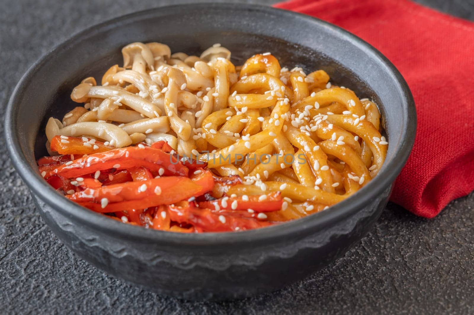 Bowl of udon noodles with bell pepper and mushrooms