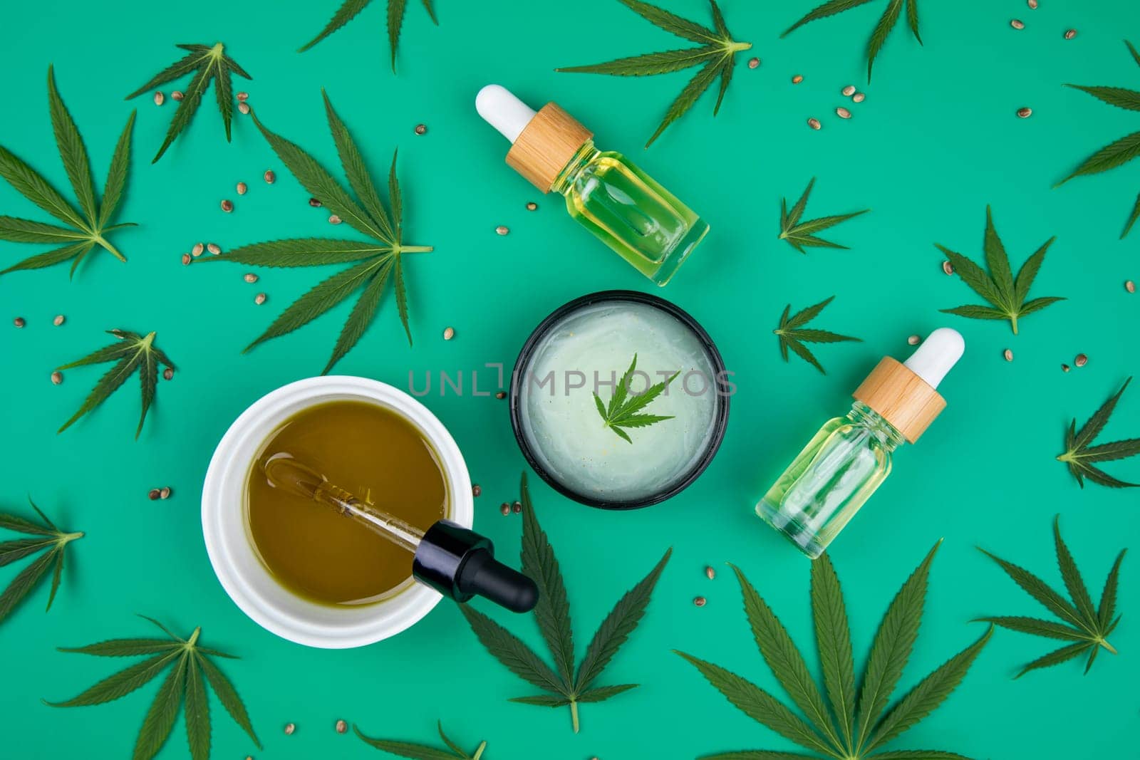 Flat lay composition of marijuana and hemp seeds on color green background