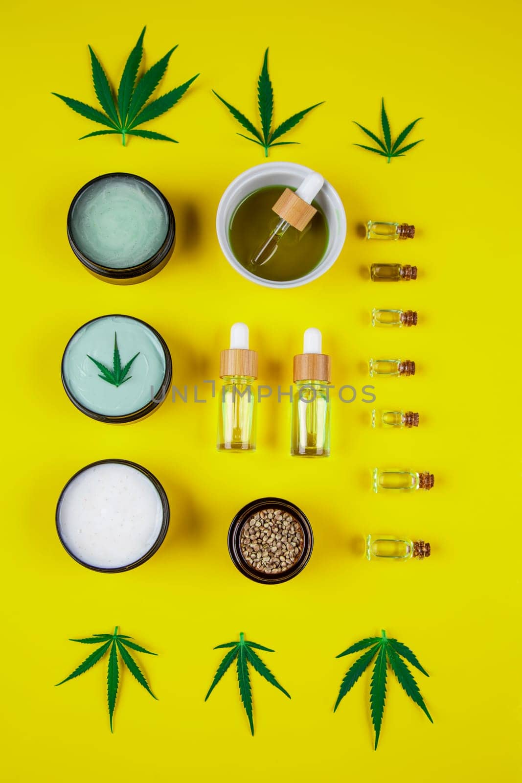 Set of essential oil in a glass bottle, with a pipette on a yellow background, top view