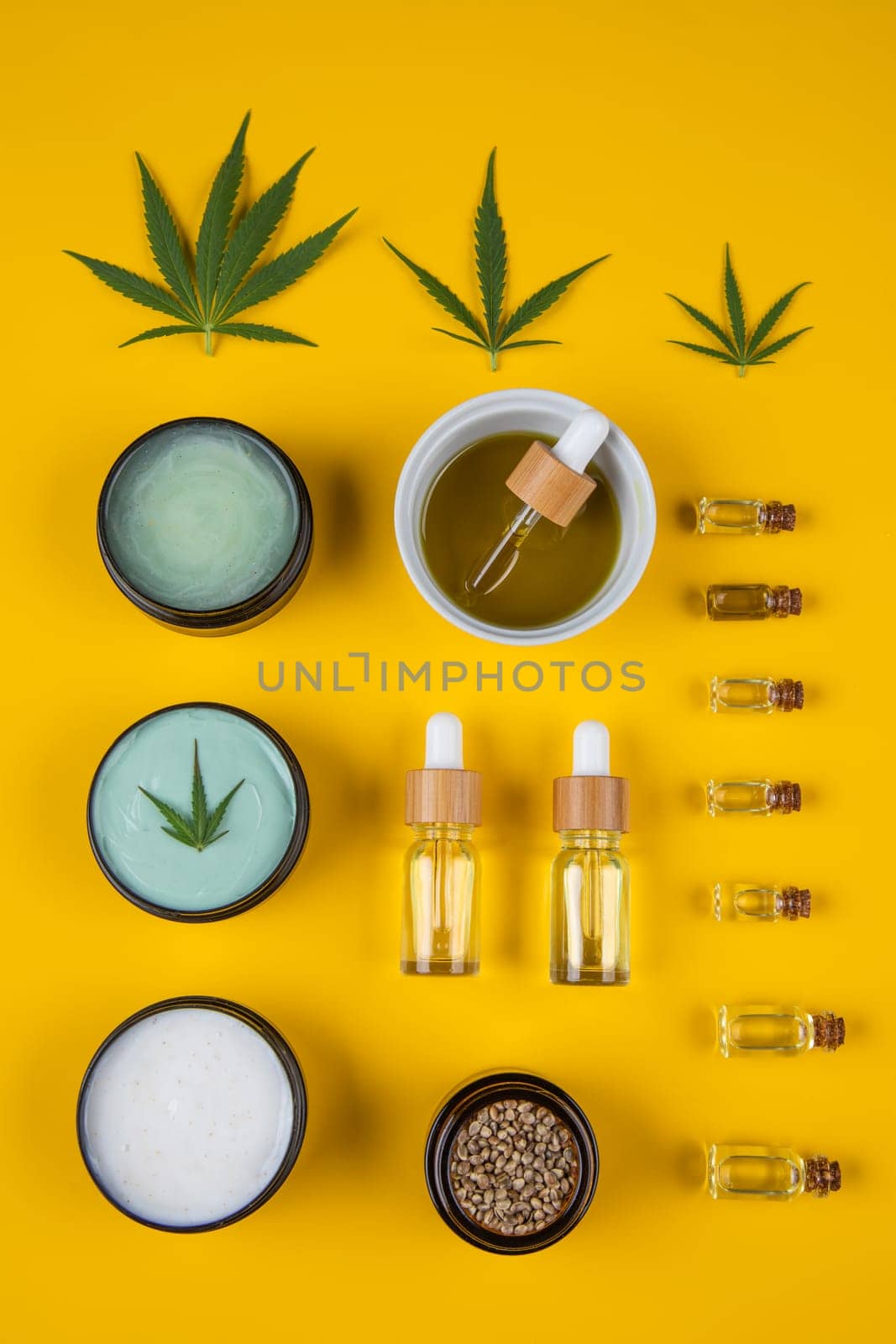 Set of essential oil in a glass bottle, with a pipette on a yellow background, top view