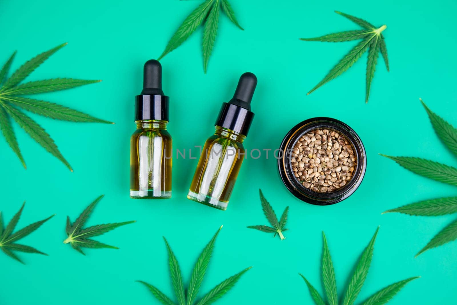 Flat lay composition with hemp oil and hemp leaves on green background