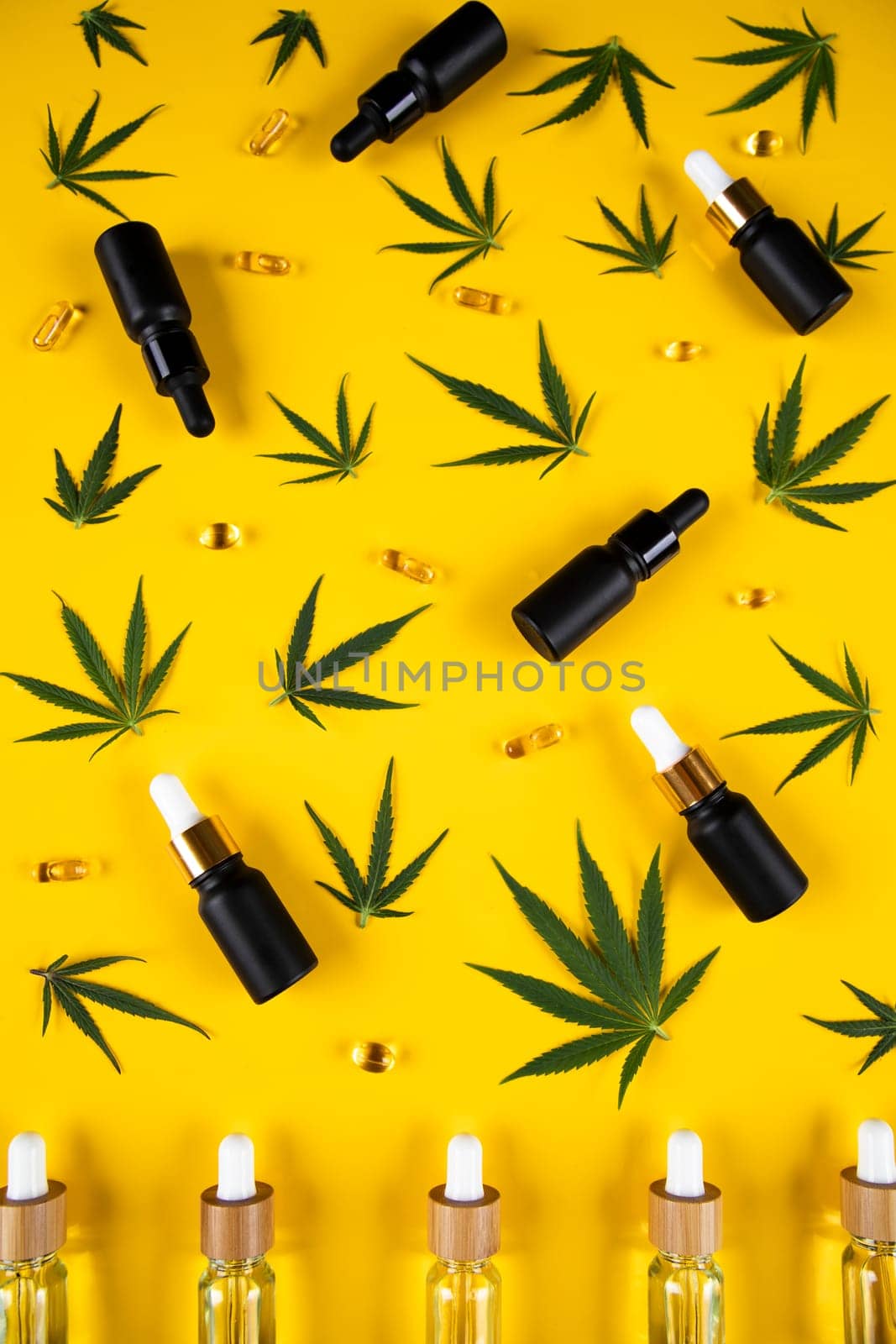 Set of essential oil in a glass bottle, with a pipette on a yellow background, top view