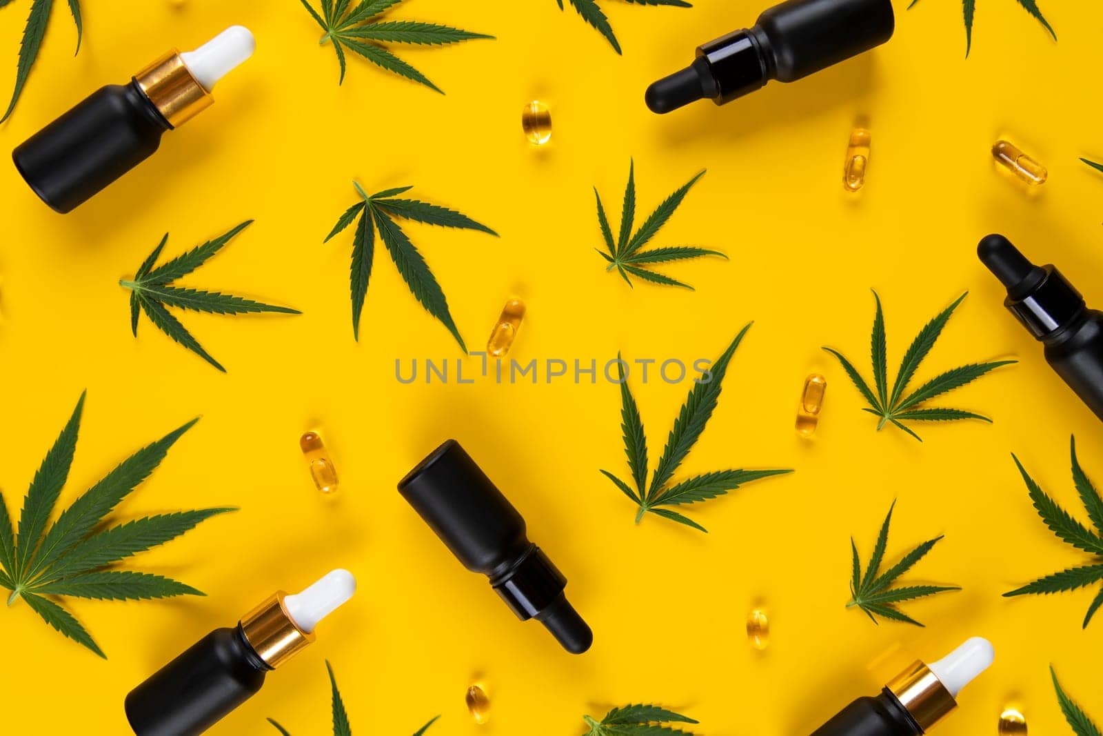 Set of essential oil in a glass bottle, with a pipette on a yellow background, top view