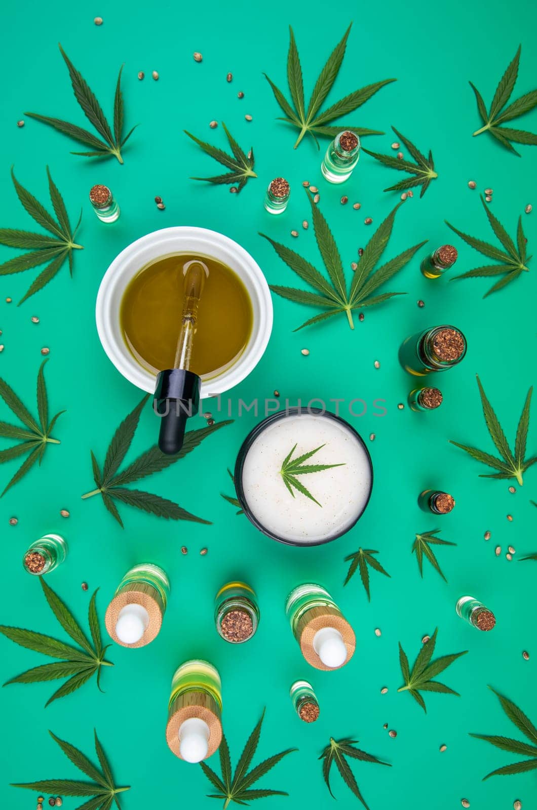 Flat lay composition with hemp oil and hemp leaves on green background