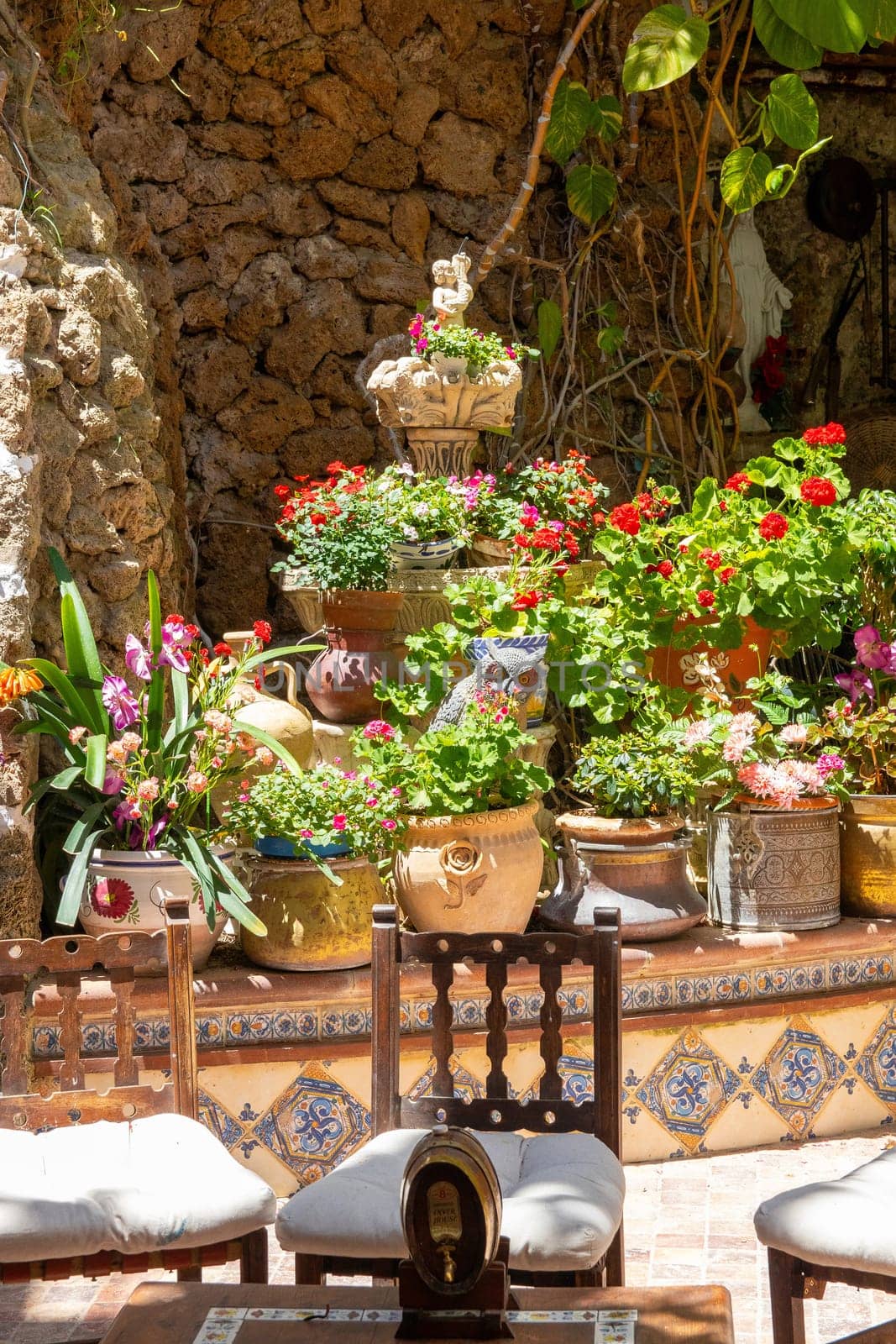 TORREMOLINOS, SPAIN, Andalusia 21 May 2019. Beautiful andalusian patio with water well flower pots and plants. Most of patio also religious images of Jesus Christ and the Virgin.
