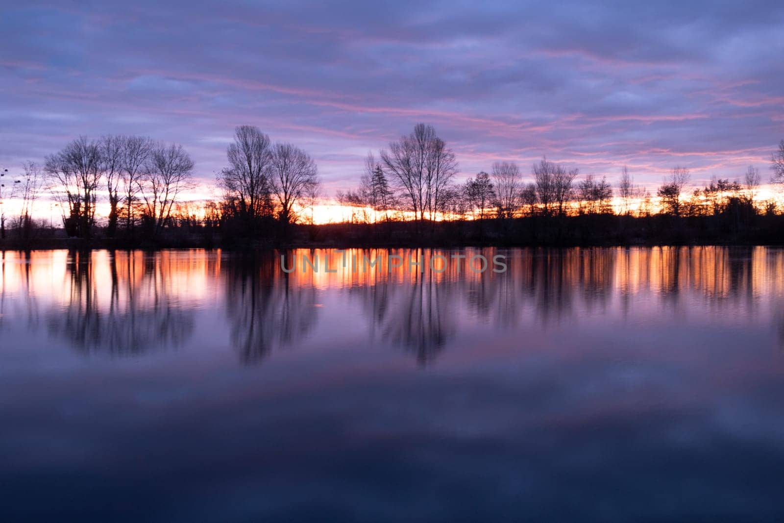 Nightscape photo of Adour French river after blazing red sunset with dramatic clouds floating. Real photography