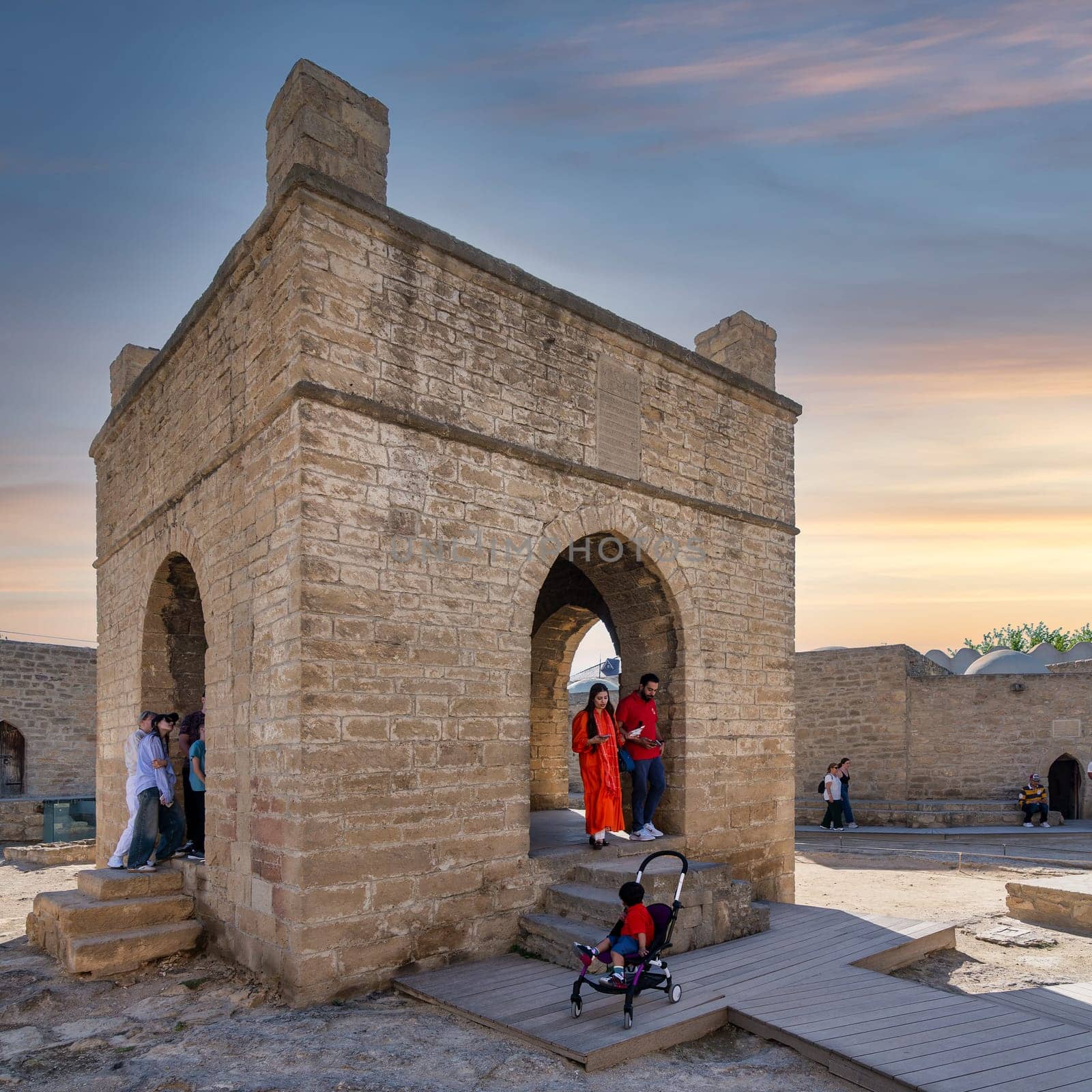 Baku, Azerbaijan - May 9, 2024: Tourists stand in the courtyard of the ancient Ateshgah Fire Temple. A young child sits in a stroller nearby