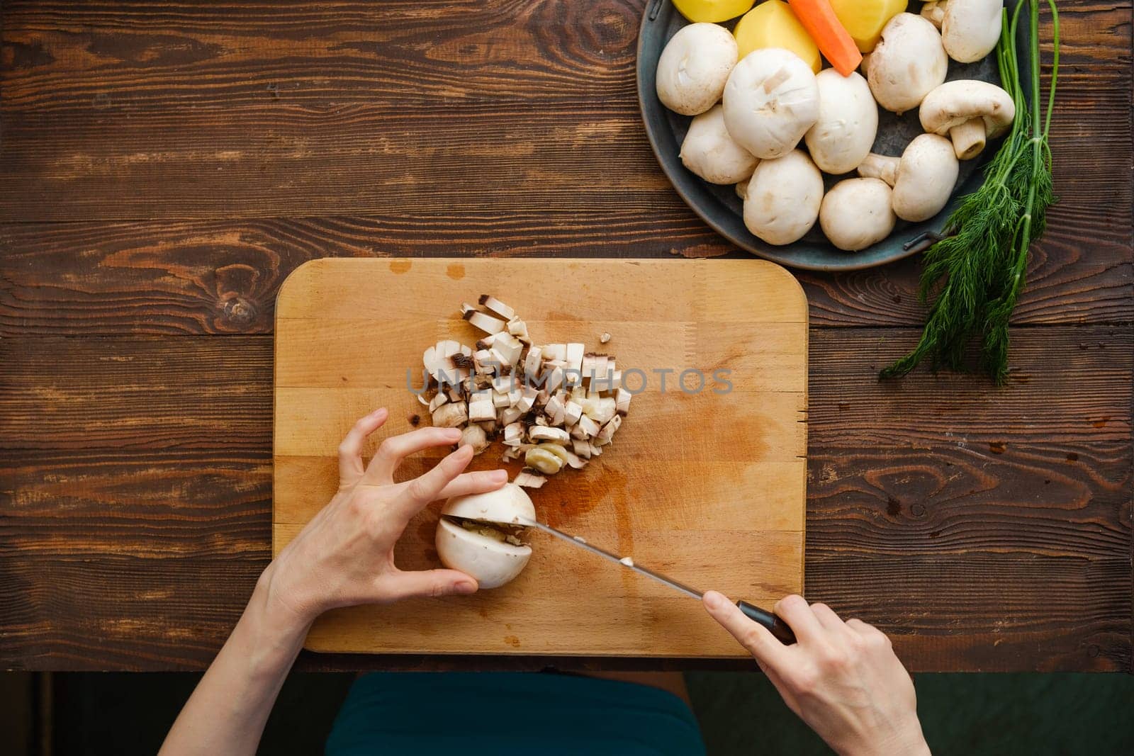 Unrecognizable woman chopping champignon mushrooms, top view