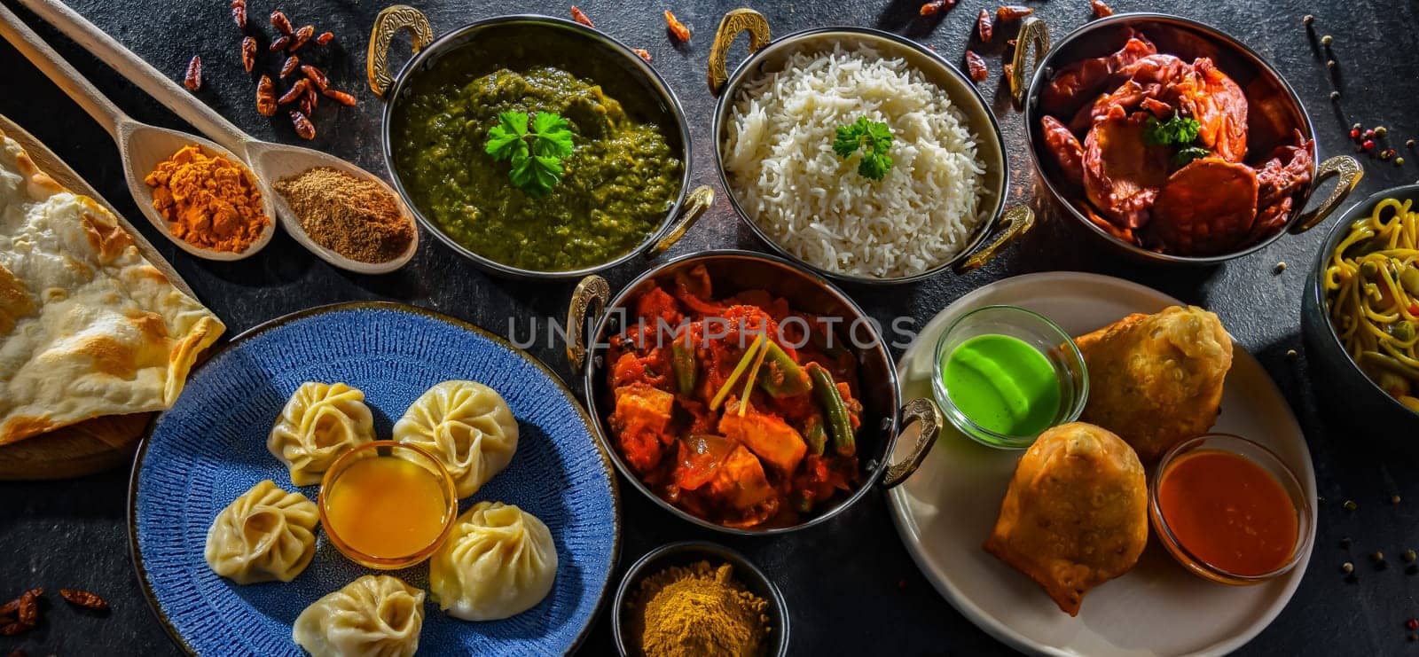Composition with indian dishes: samosa, pakora, palak paneer, jalfrezi, thukpa and naan bread