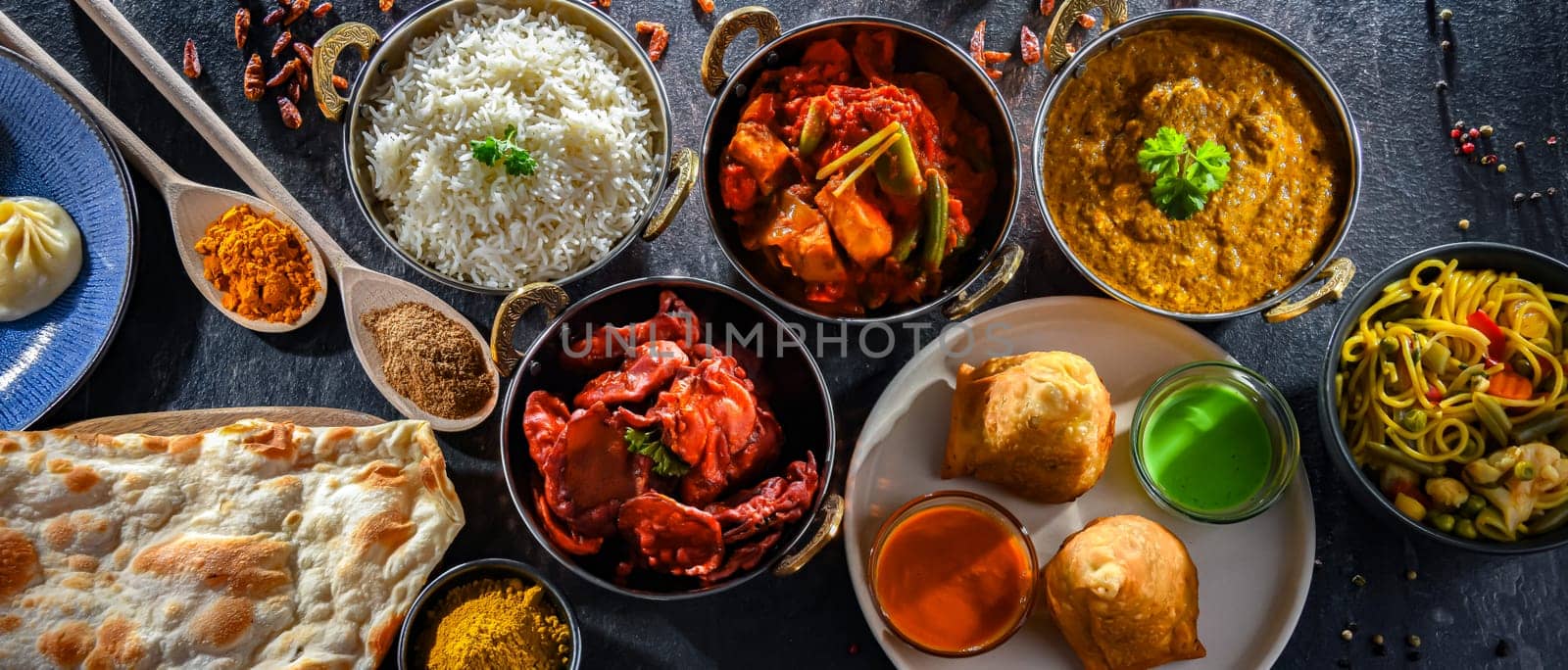 Composition with indian dishes: samosa, pakora, palak paneer, jalfrezi, thukpa and naan bread