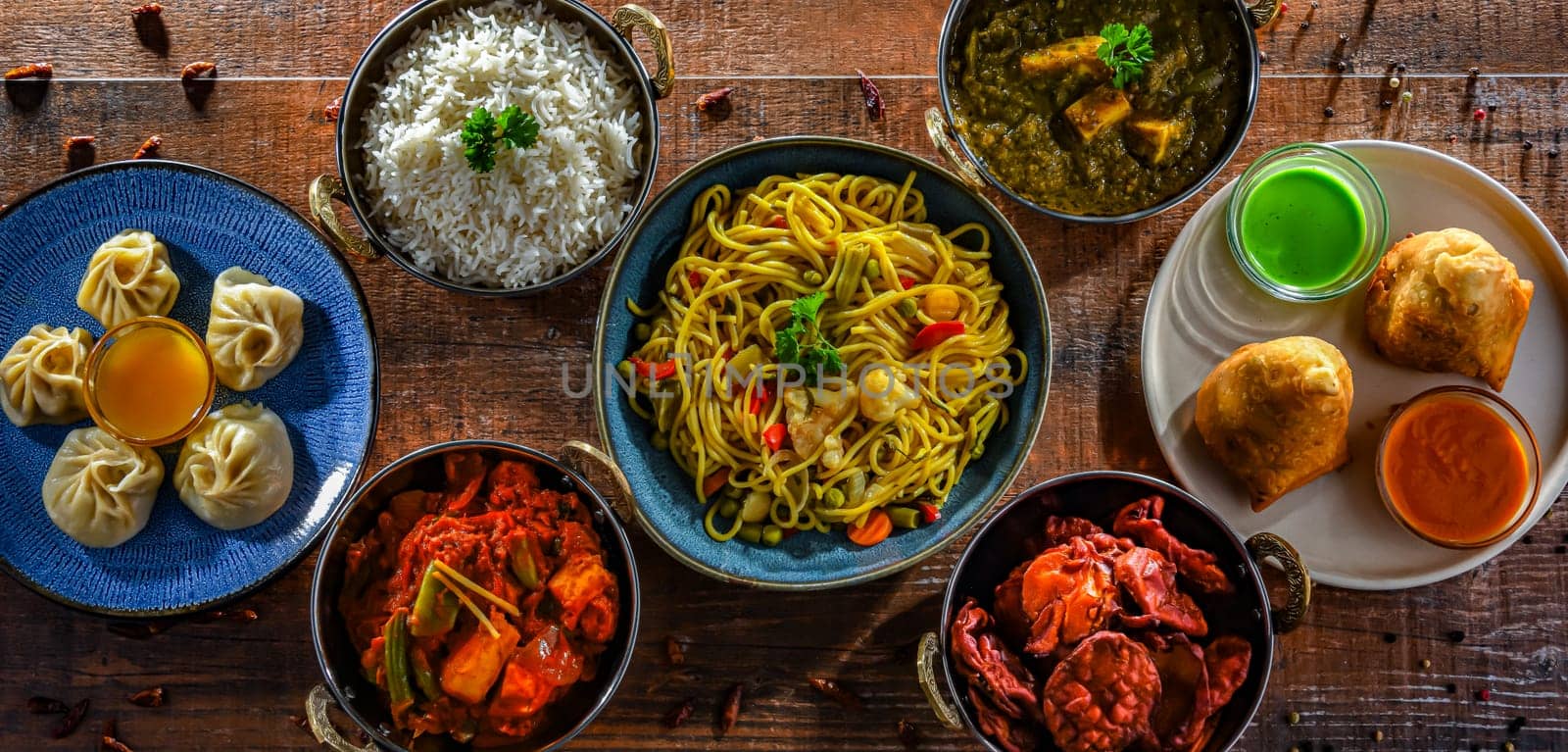 Composition with indian dishes: samosa, pakora, palak paneer, jalfrezi, thukpa and naan bread