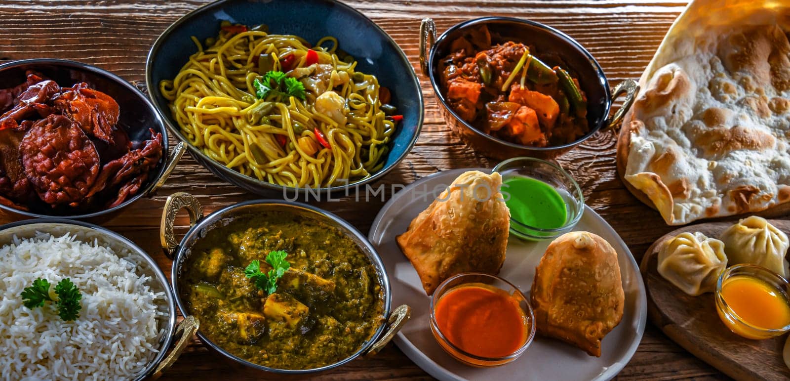 Composition with indian dishes: samosa, pakora, palak paneer, jalfrezi, thukpa and naan bread