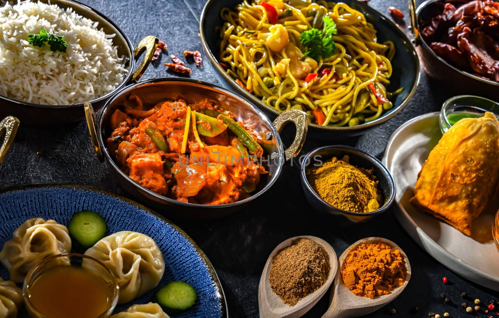 Composition with indian dishes: samosa, pakora, palak paneer, jalfrezi, thukpa and naan bread