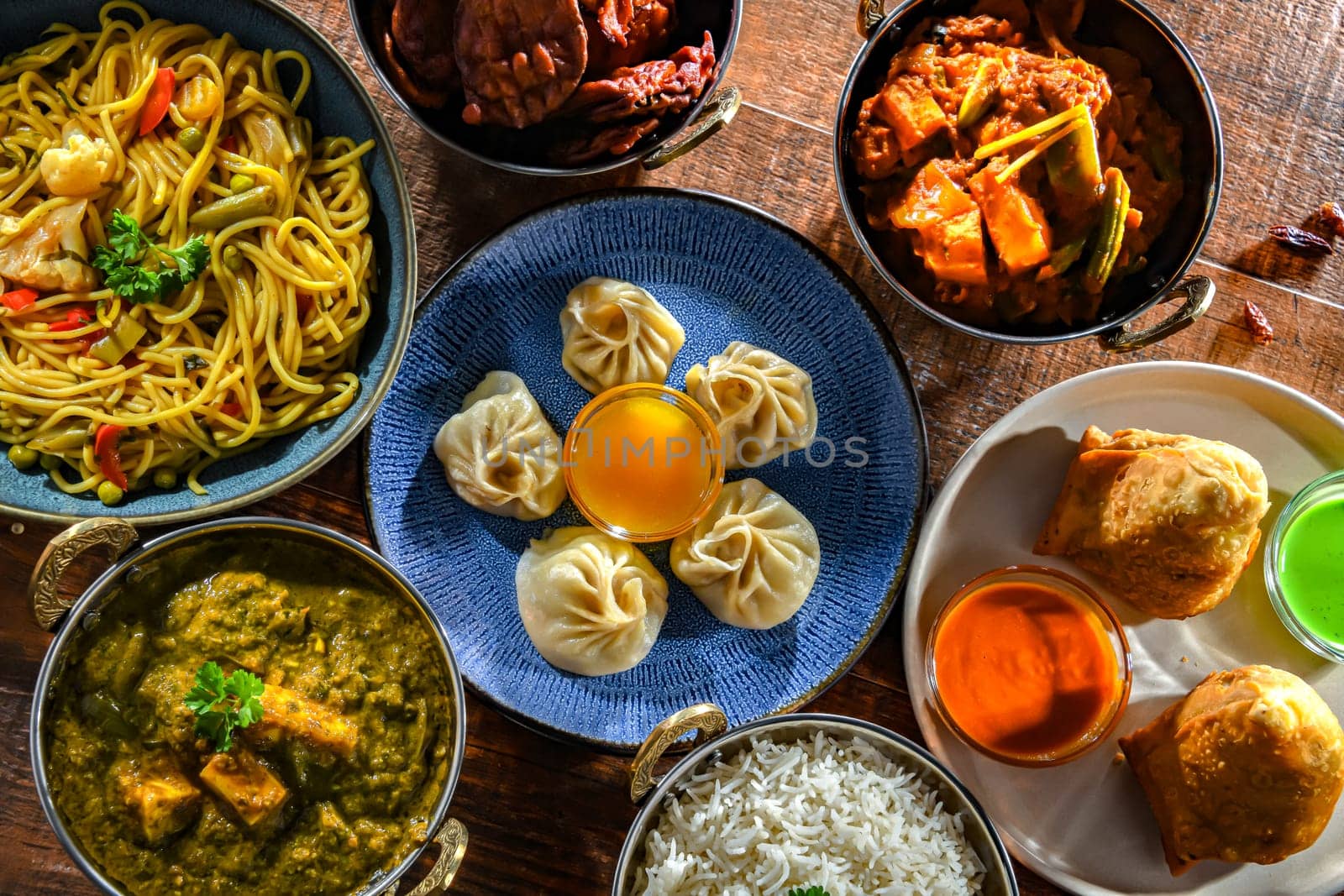 Composition with indian dishes: samosa, pakora, palak paneer, jalfrezi, thukpa and naan bread