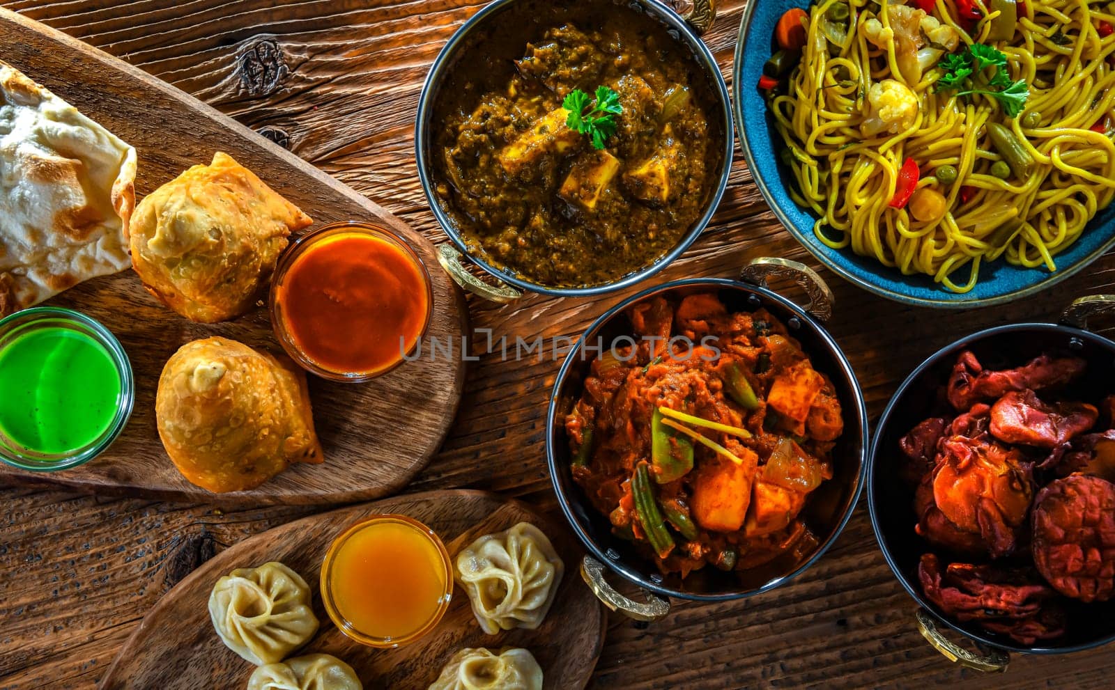 Composition with indian dishes: samosa, pakora, palak paneer, jalfrezi, thukpa and naan bread
