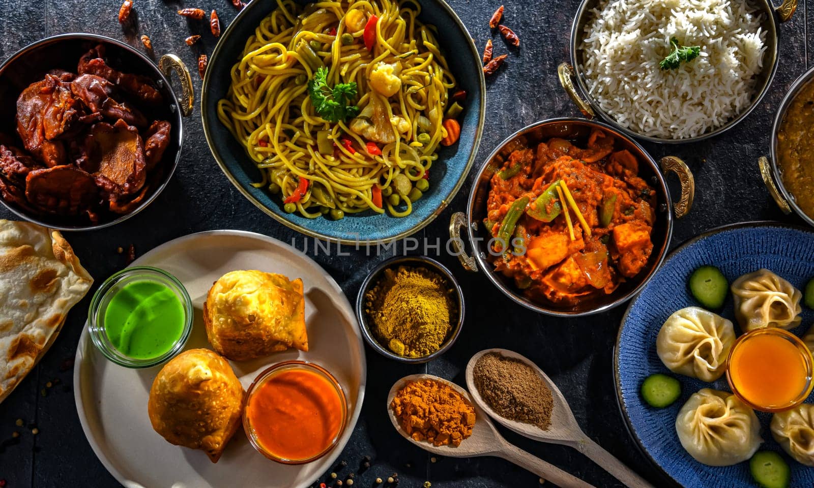 Composition with indian dishes: samosa, pakora, palak paneer, jalfrezi, thukpa and naan bread