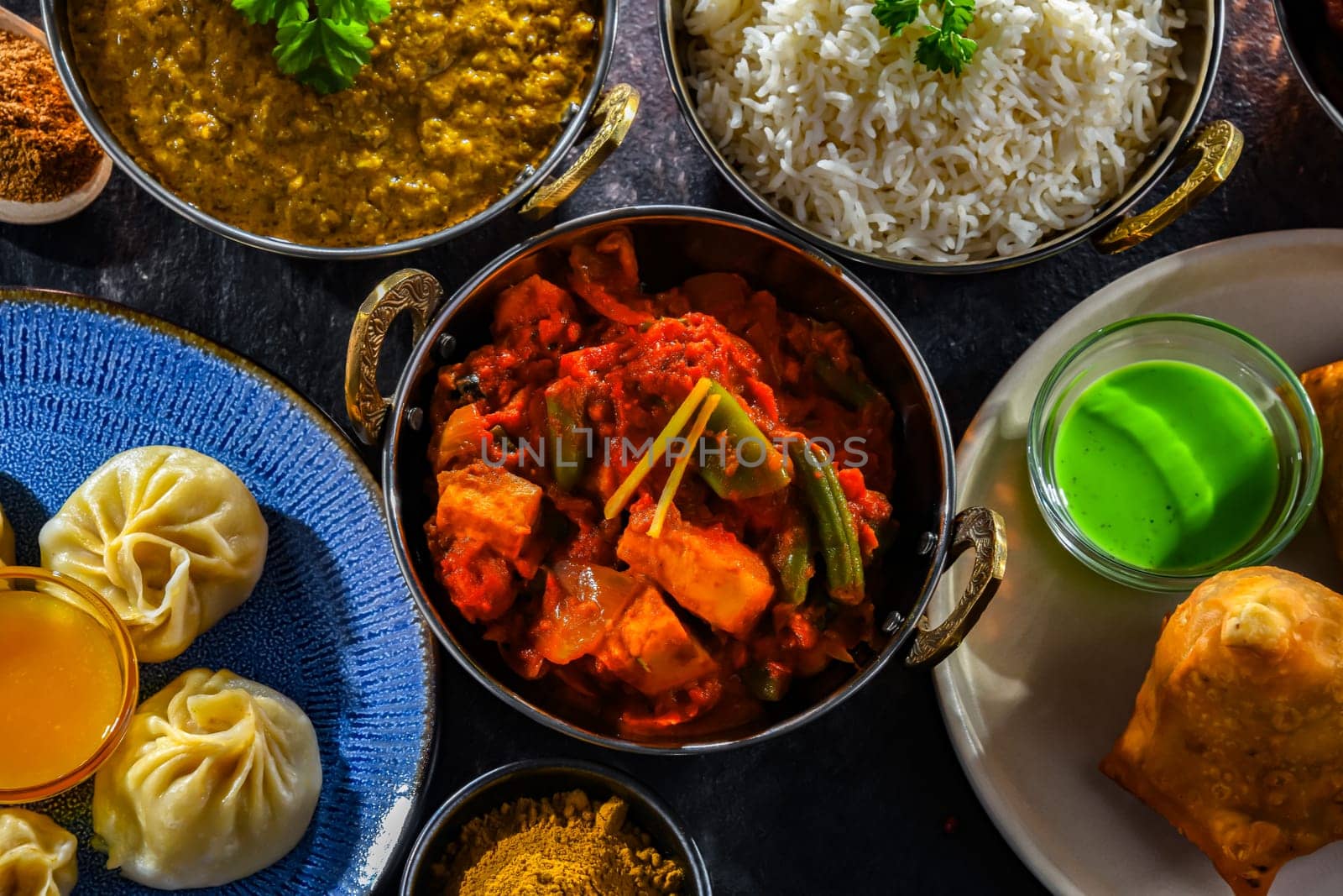 Composition with indian dishes: samosa, pakora, palak paneer, jalfrezi, thukpa and naan bread