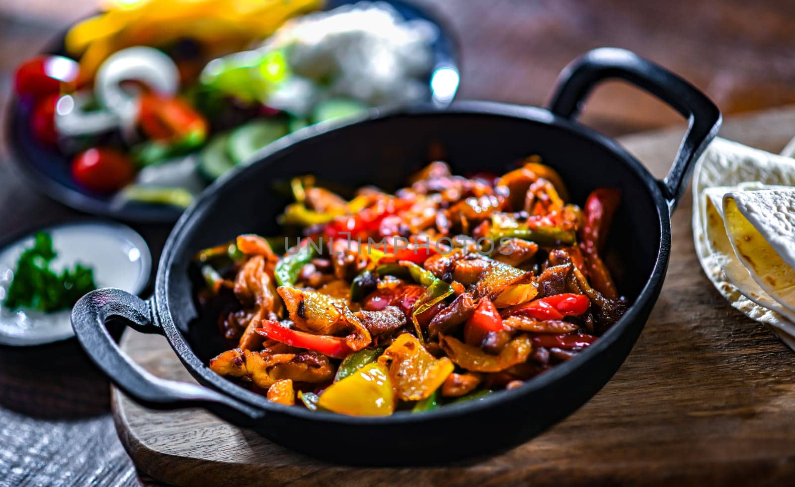 Fajita with stripped peppers and onions served on a hot iron skillet