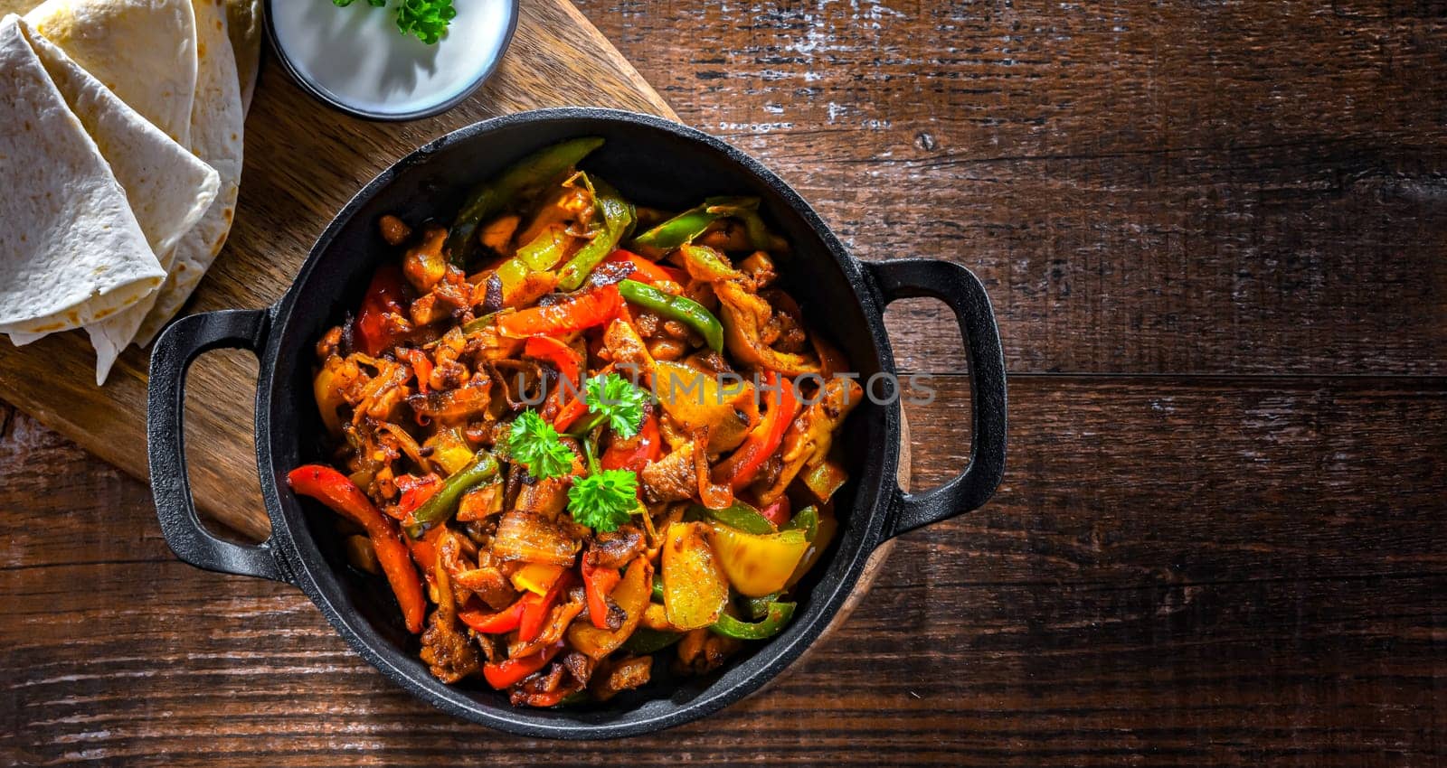 Fajita with stripped peppers and onions served on a hot iron skillet