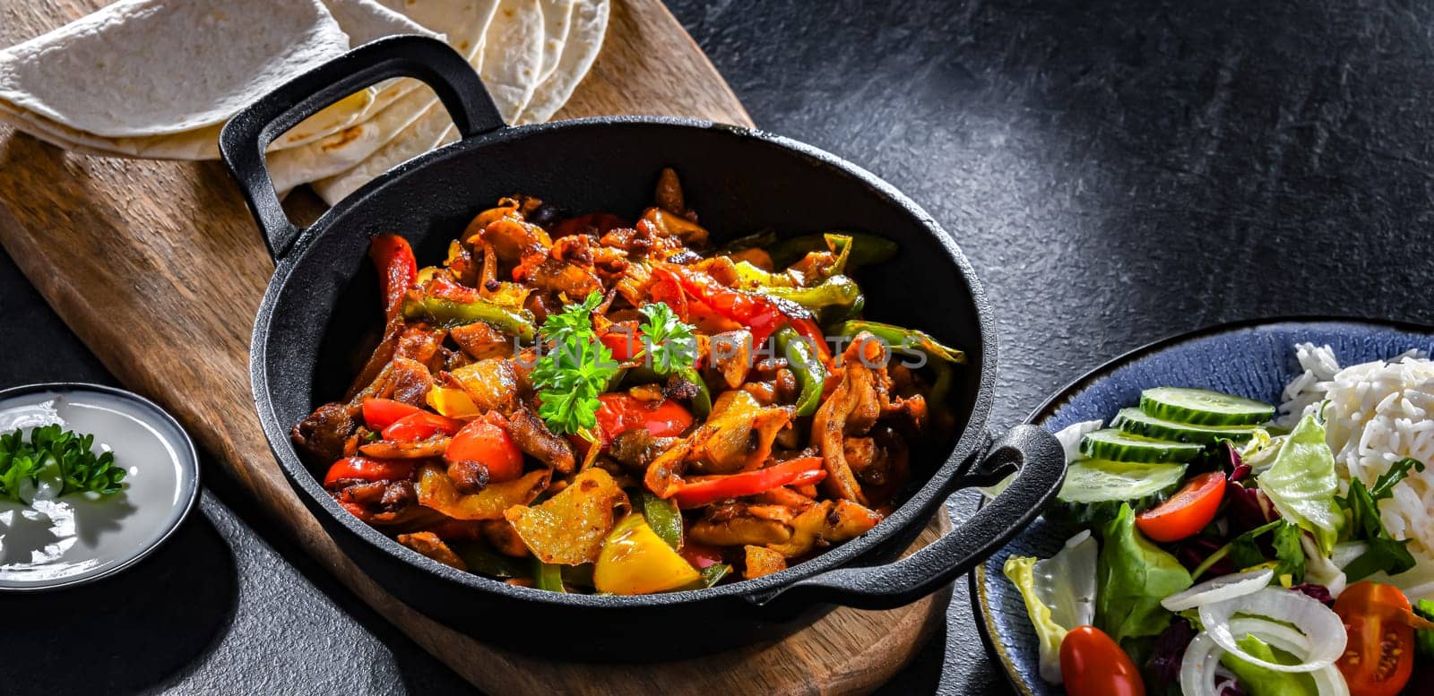 Fajita with stripped peppers and onions served on a hot iron skillet