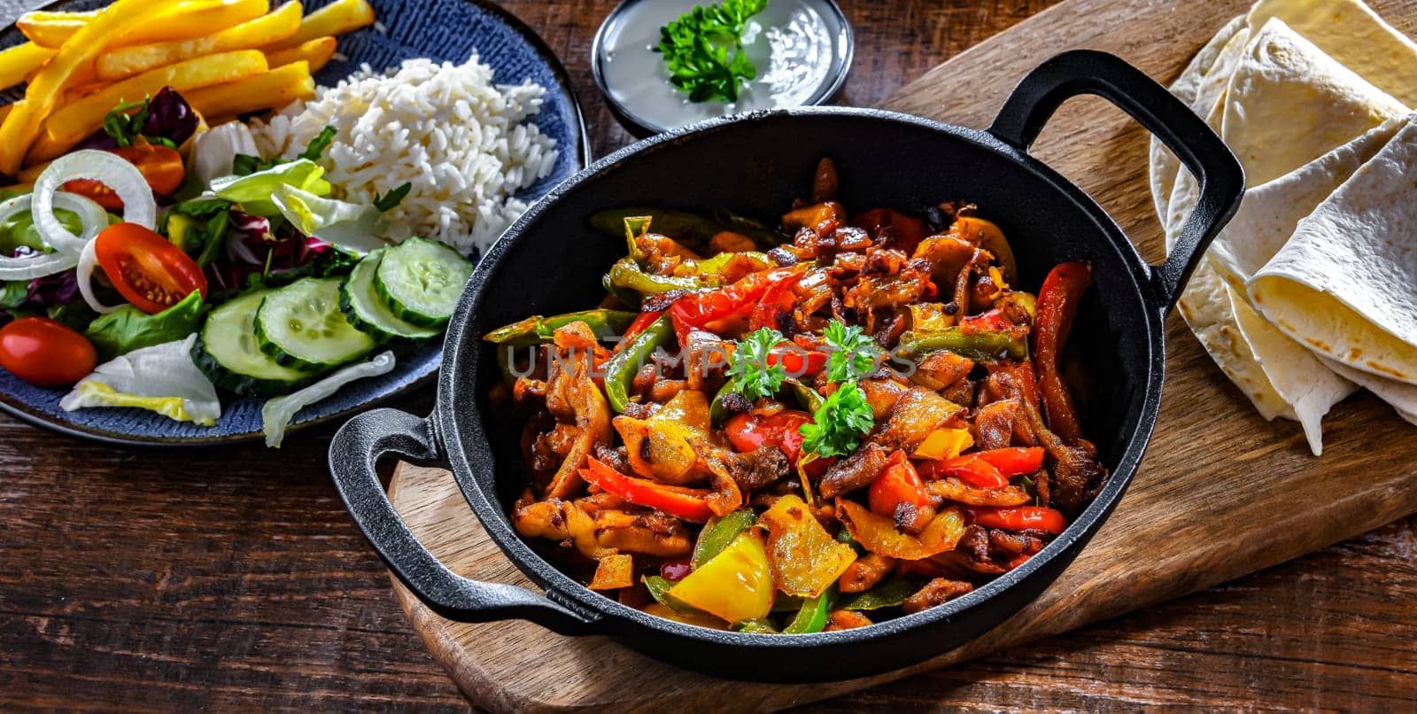 Fajita with stripped peppers and onions served on a hot iron skillet