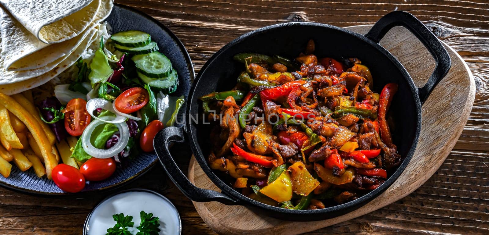 Fajita with stripped peppers and onions served on a hot iron skillet