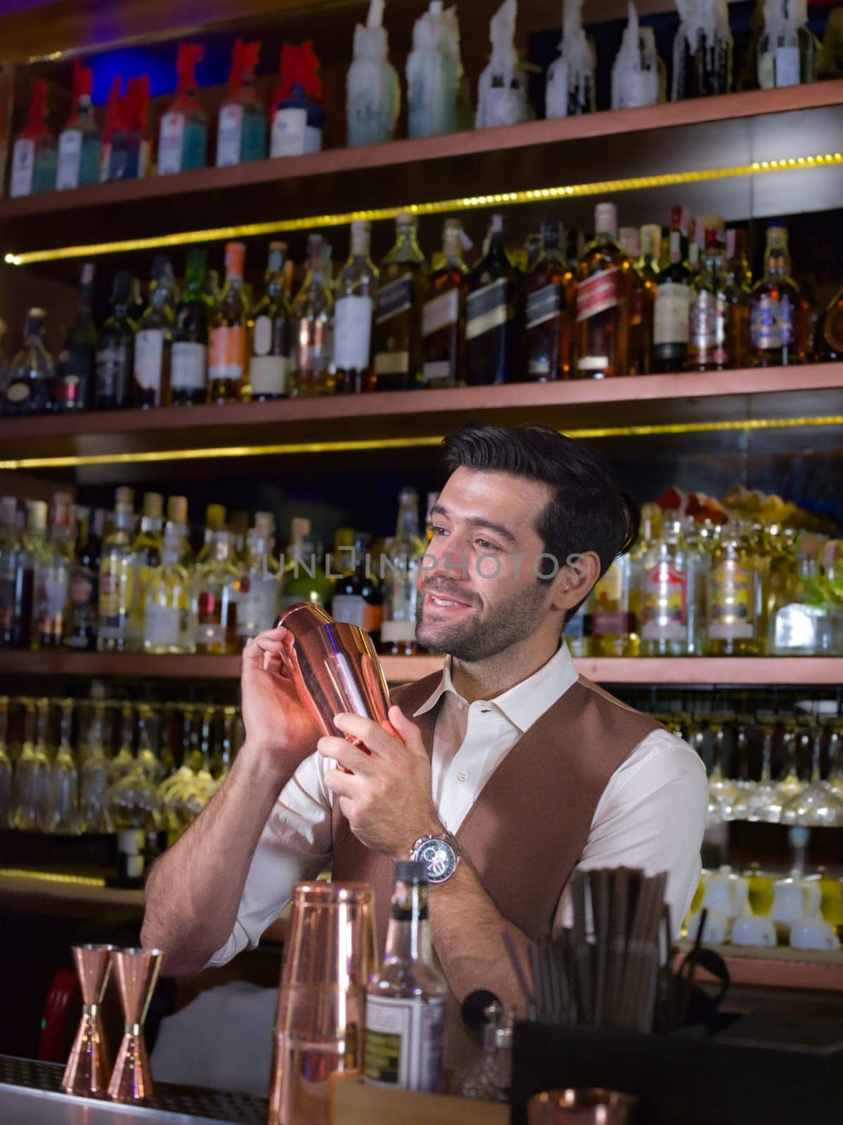 Bartender is making cocktail with talking customer at bar counter