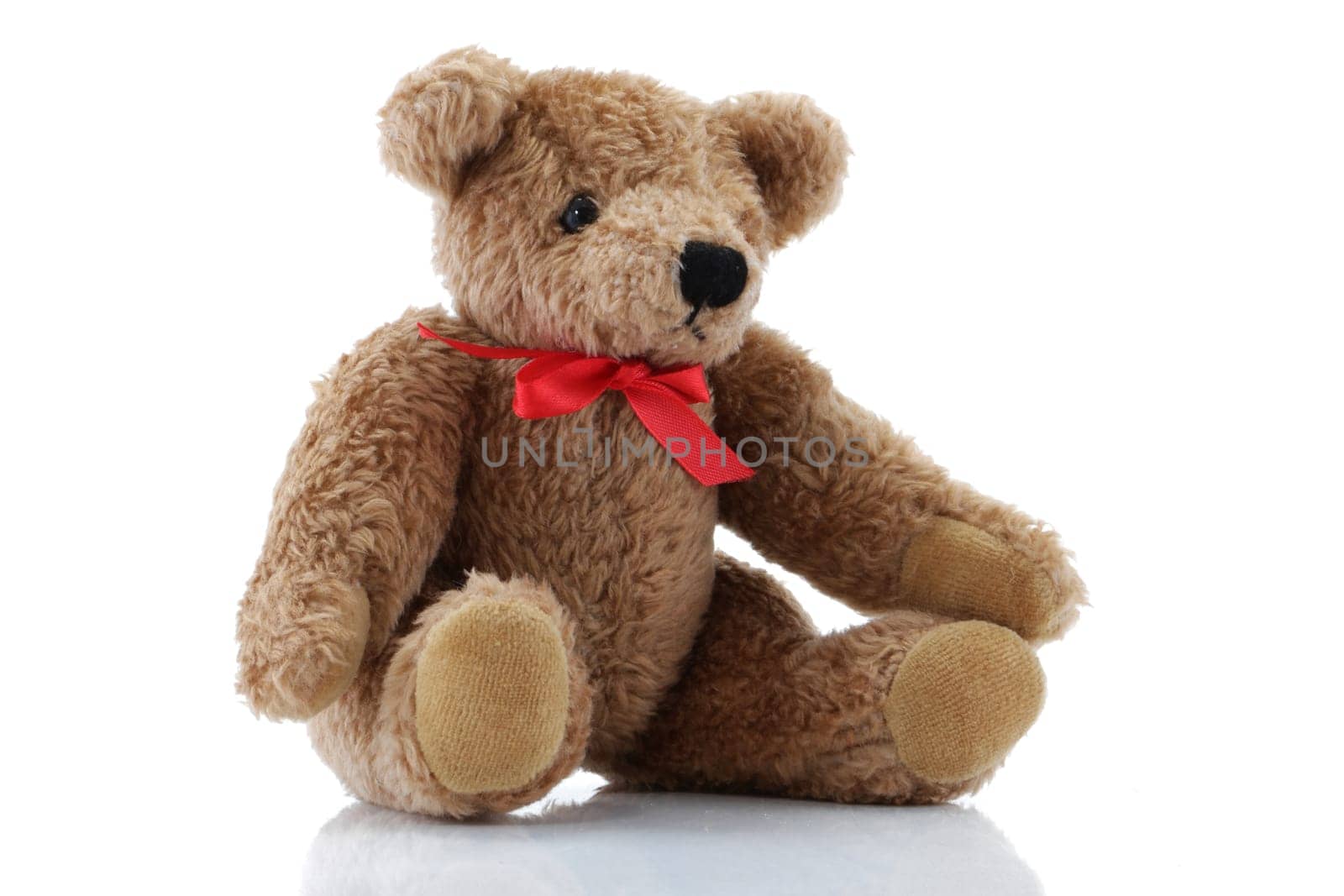A Brown Teddy Bear with a red bow sitting