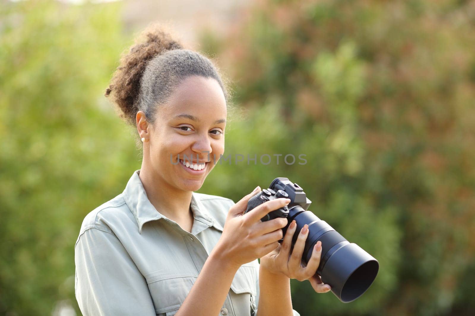 Happy black photographer looks at camera in a park