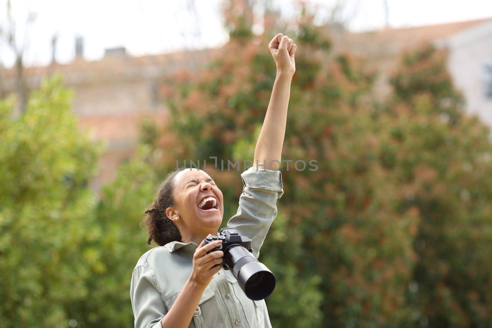 Excited black photographer celebrating success raising arm