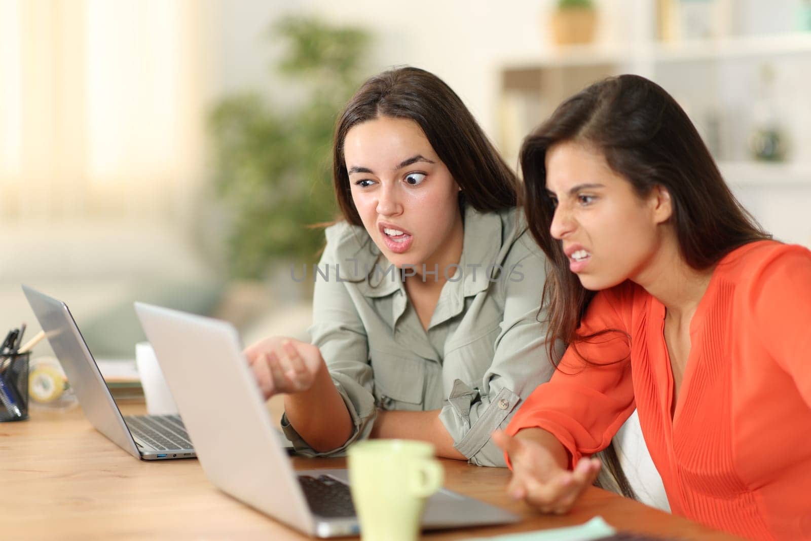 Two upset tele workers working checking laptop strange content at home