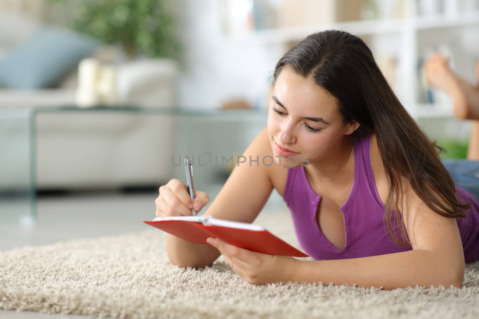 Woman is writing in agenda on the floor at home