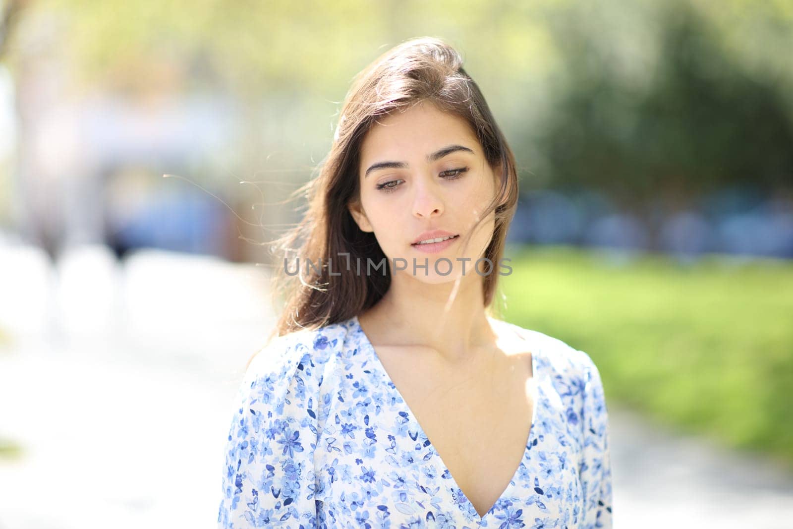 Front view portrait of a pensive distracted woman walking in the street