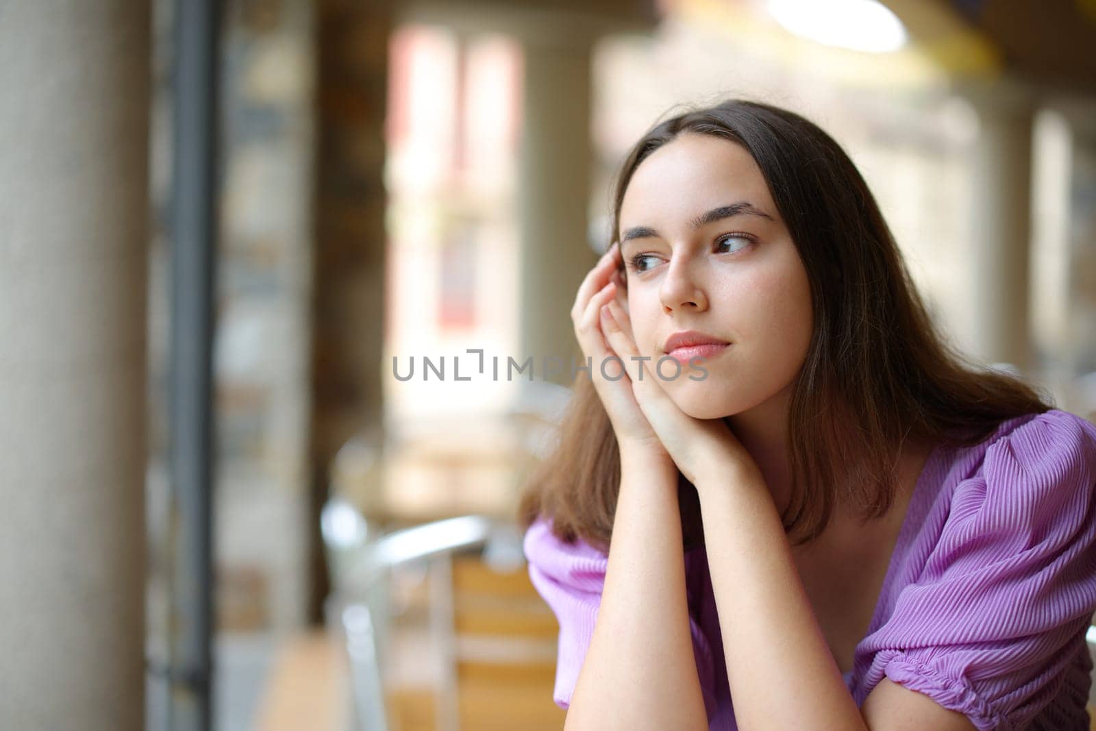 Pensive woman dreaming looking away in a cofee shop terrace