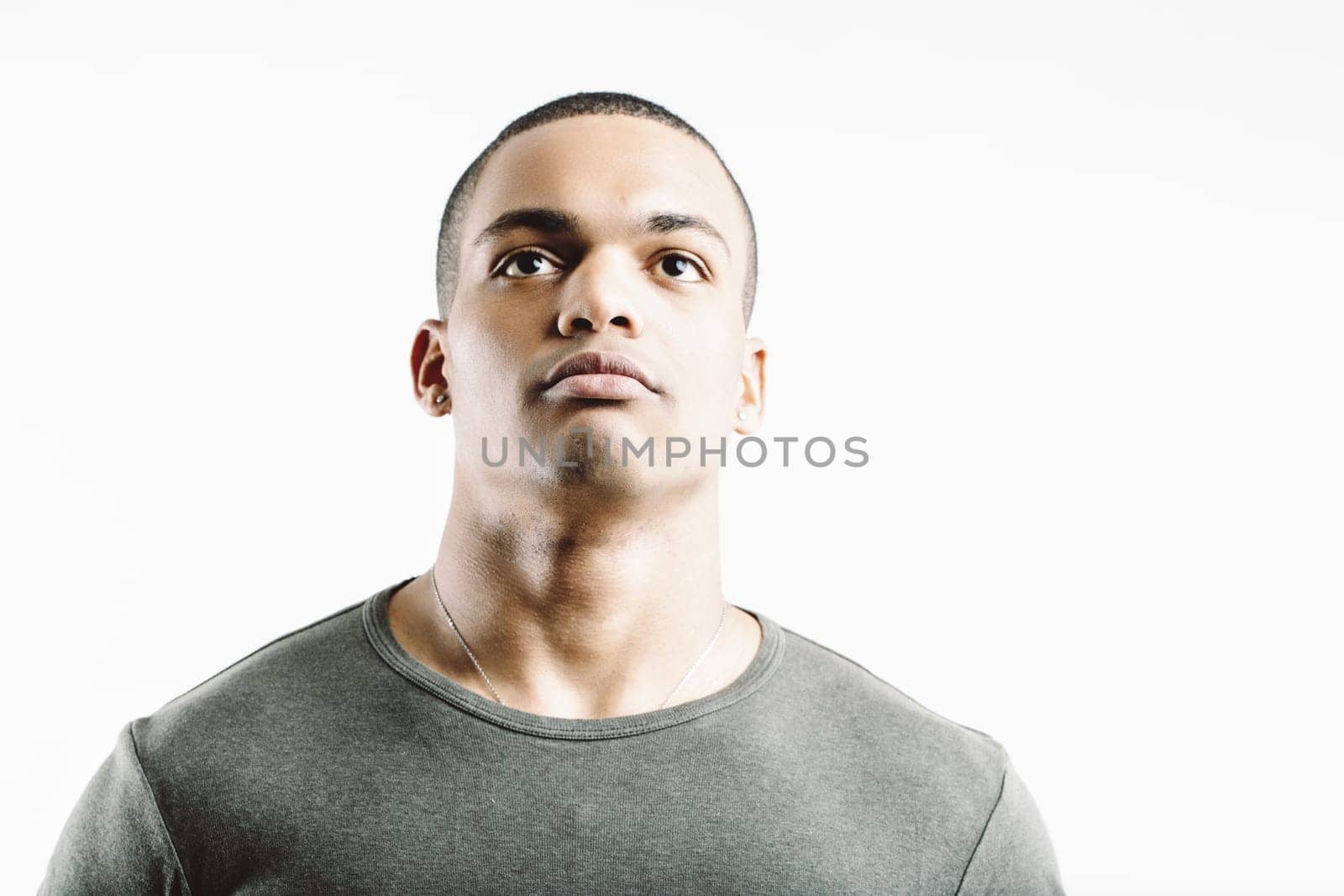 Man in a green t-shirt and beige pants, standing with a stern look. His strong, disciplined stance conveys a martial presence, emphasizing physical fitness and mental toughness