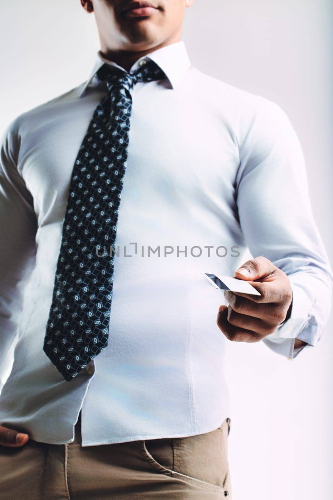 Confident young man in a white shirt and patterned tie, presenting a business card. His professional appearance suggests he is ready for networking and business engagements