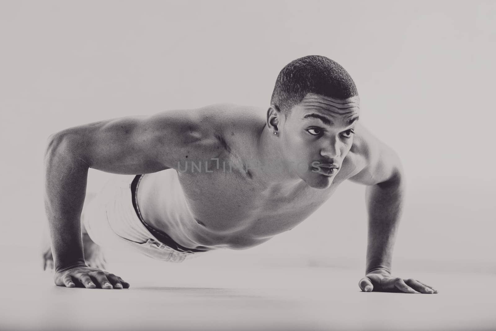 Black man in a 1950s style, performing a push-up with intense focus. His muscular build and serious expression reflect his dedication as a boxer training for strength and endurance