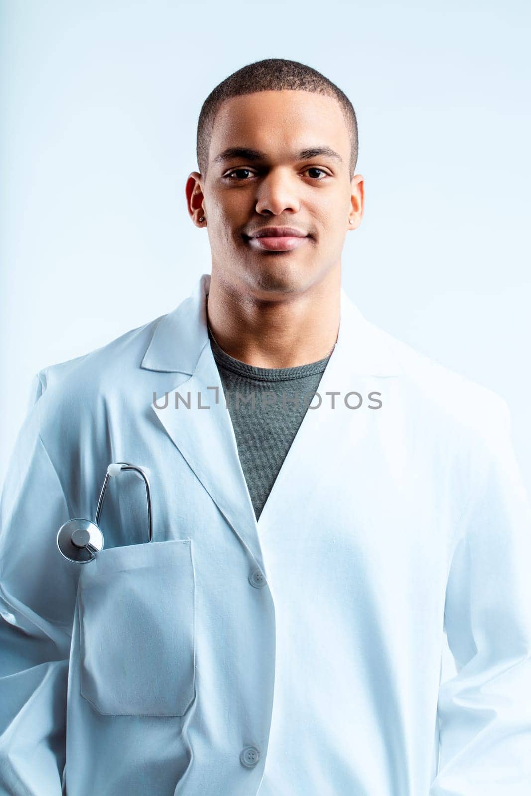 Man in a white lab coat with a stethoscope, smiling confidently. His calm and professional appearance suggests competence and a welcoming attitude in a medical setting
