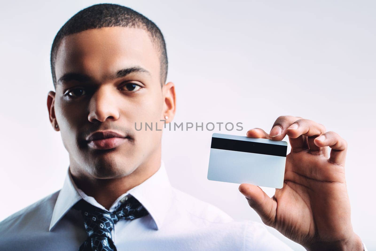 Individual in a white dress shirt and patterned tie, presenting a business card. His confident look and professional appearance suggest readiness for business or networking opportunities