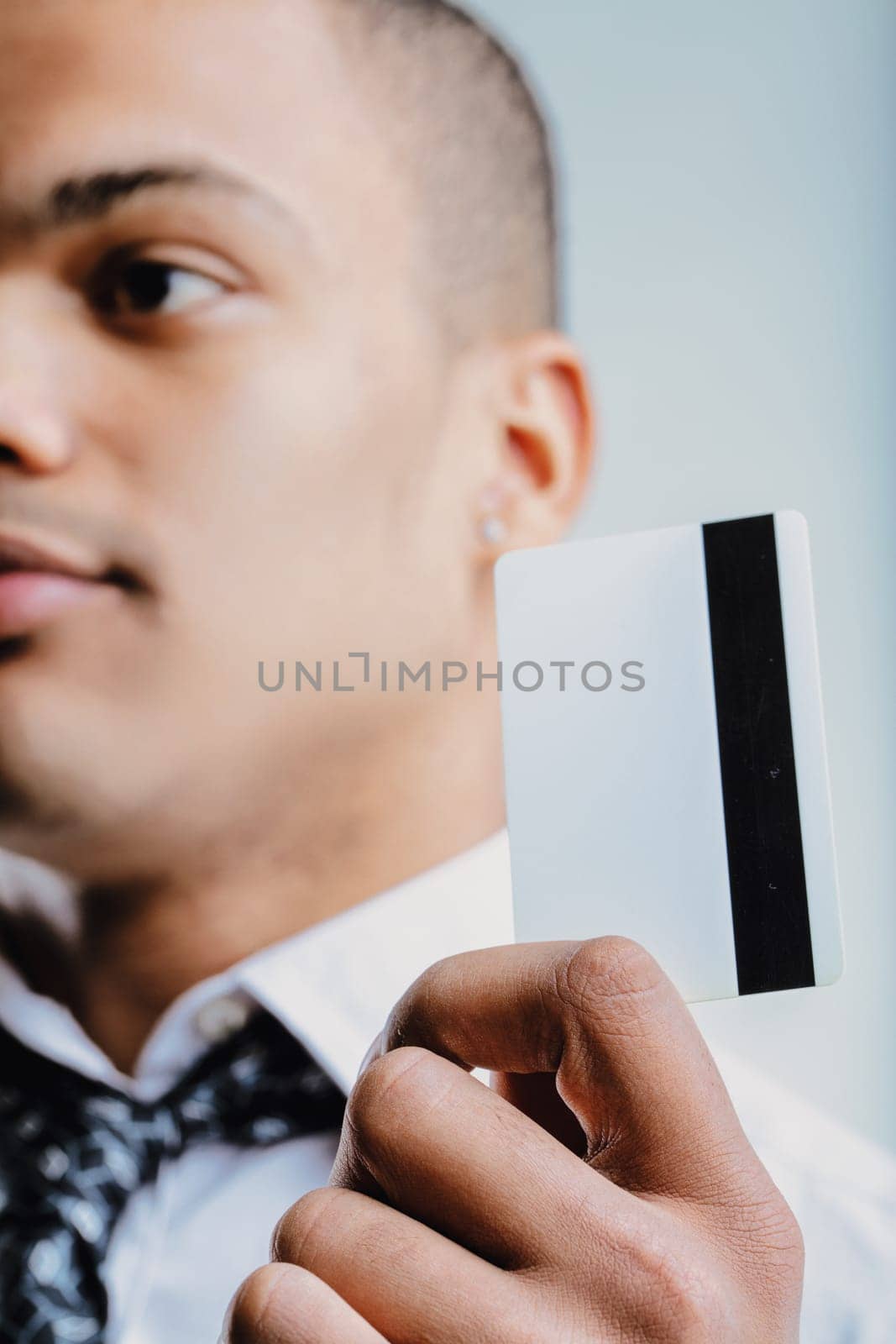 Man in a white shirt with a patterned tie, extending a business card. His confident demeanor and formal attire indicate he is prepared for professional engagements and networking