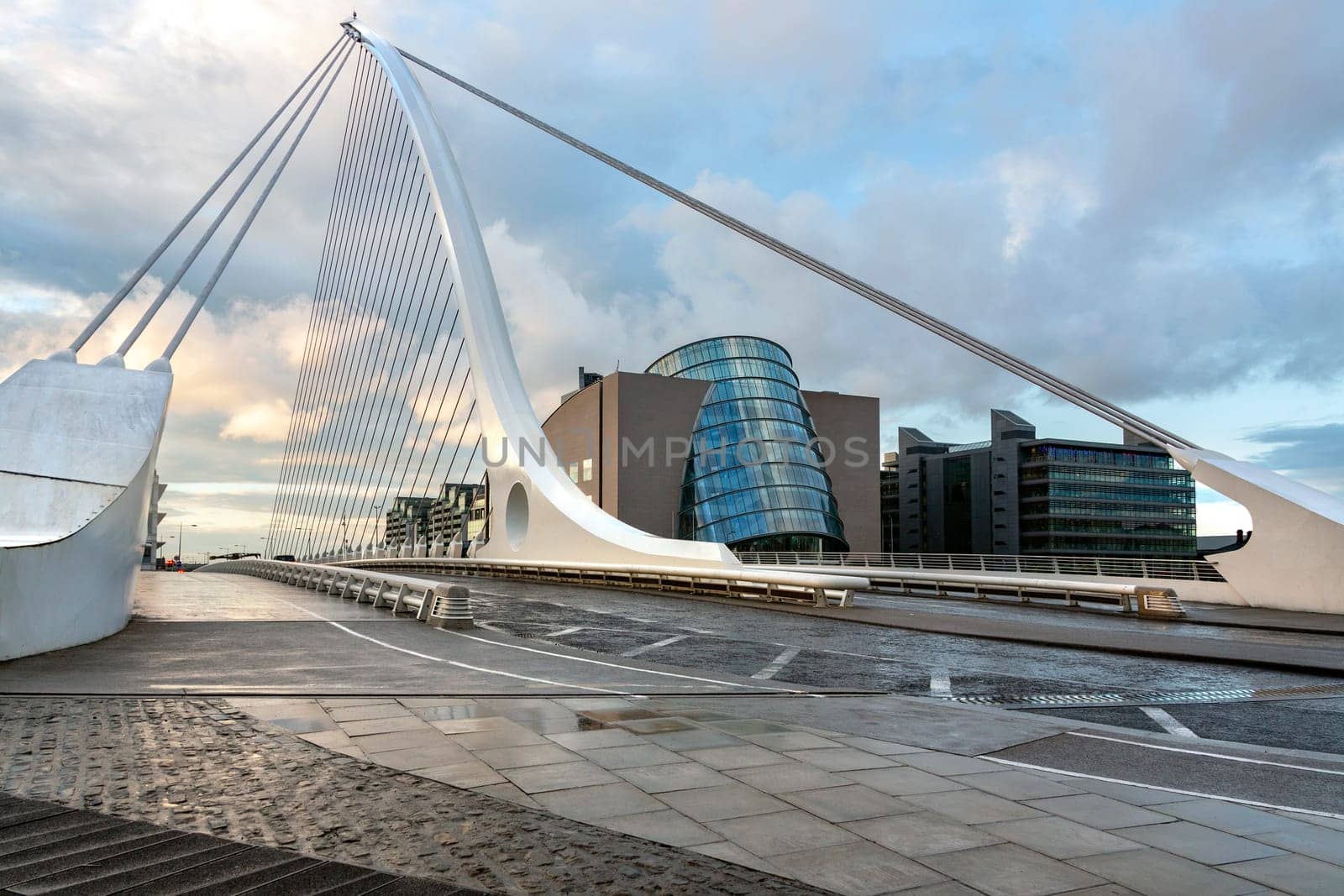 The Samuel Beckett Bridge and the building on the waterfront near the Convention Center - Dublin city center in the Republic of Ireland. This is a cable-stayed bridge that joins Sir John Rogerson's Quay on the south side of the River Liffey to Guild Street and North Wall Quay in the Docklands area. The innovative architect Santiago Calatrava designed this and a number of other bridges and buildings in Ireland.